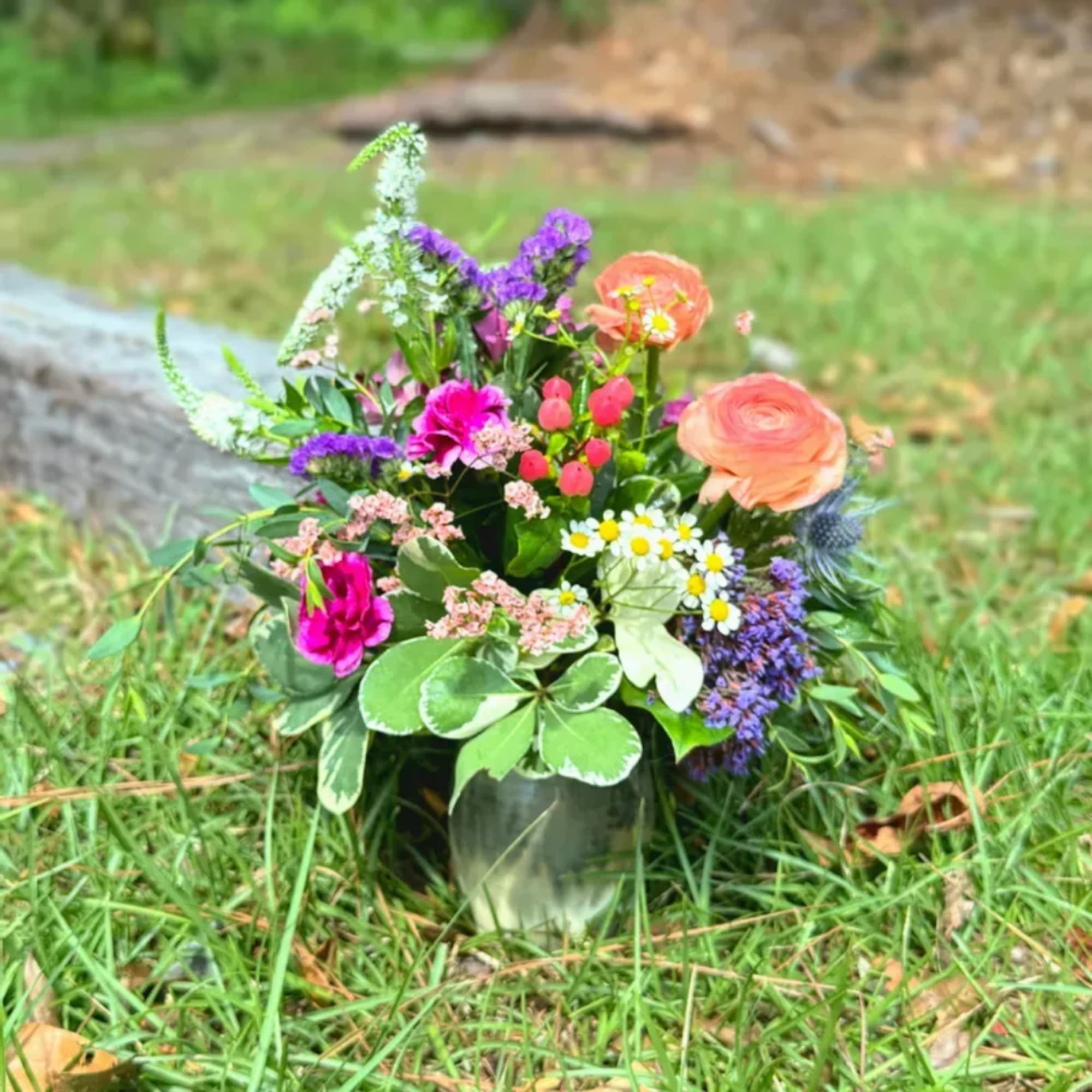 Mixed bouquet of pink, purple, and peach flowers in a glass vase