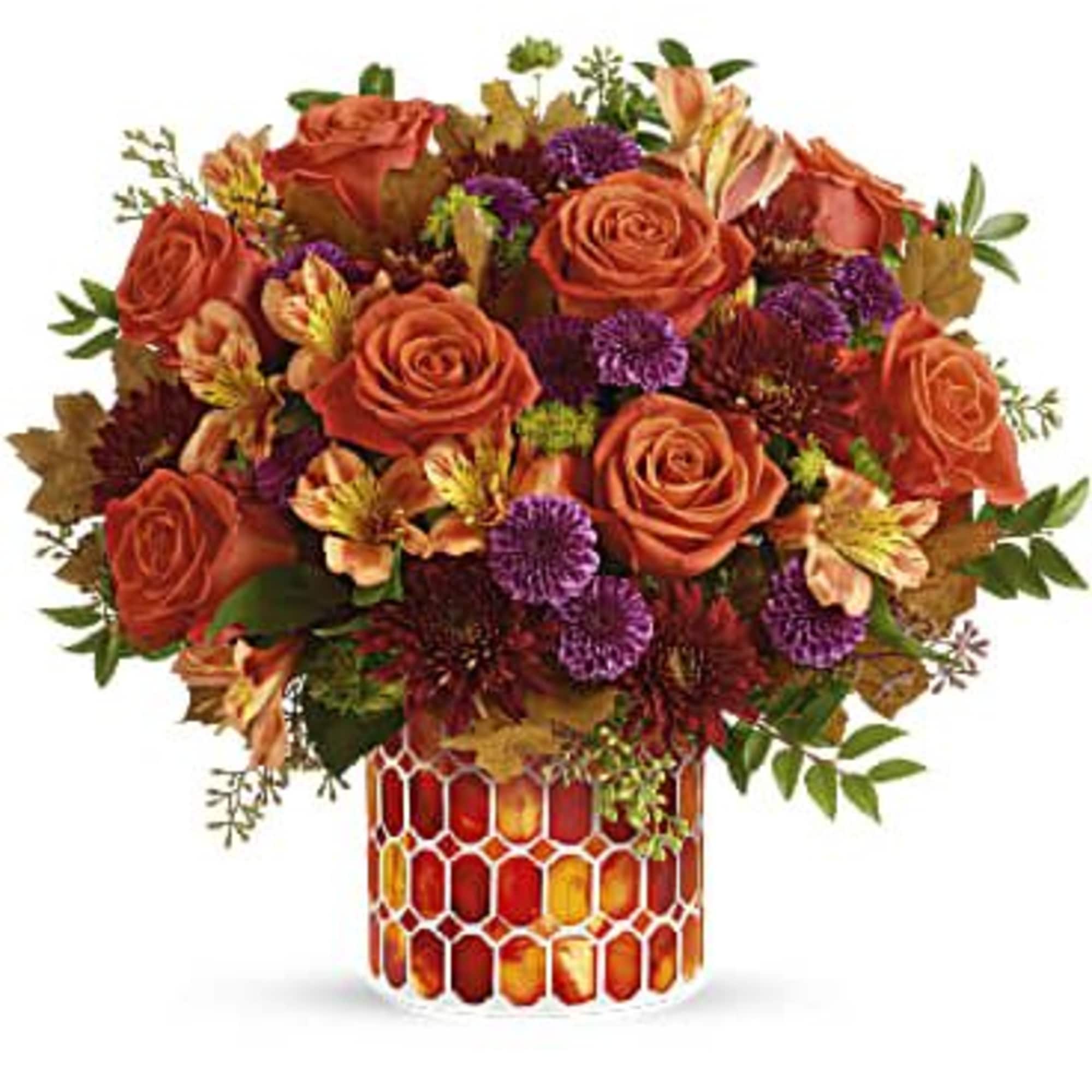 Orange roses and purple flowers in a patterned vase