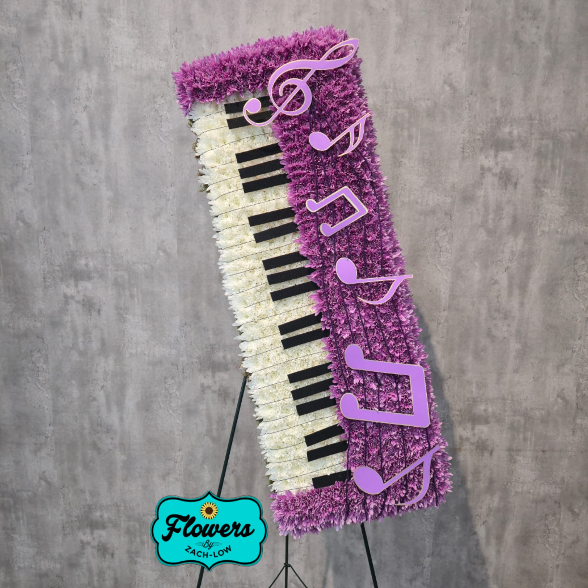 Tall floral arrangement shaped like a piano keyboard with purple and white flowers