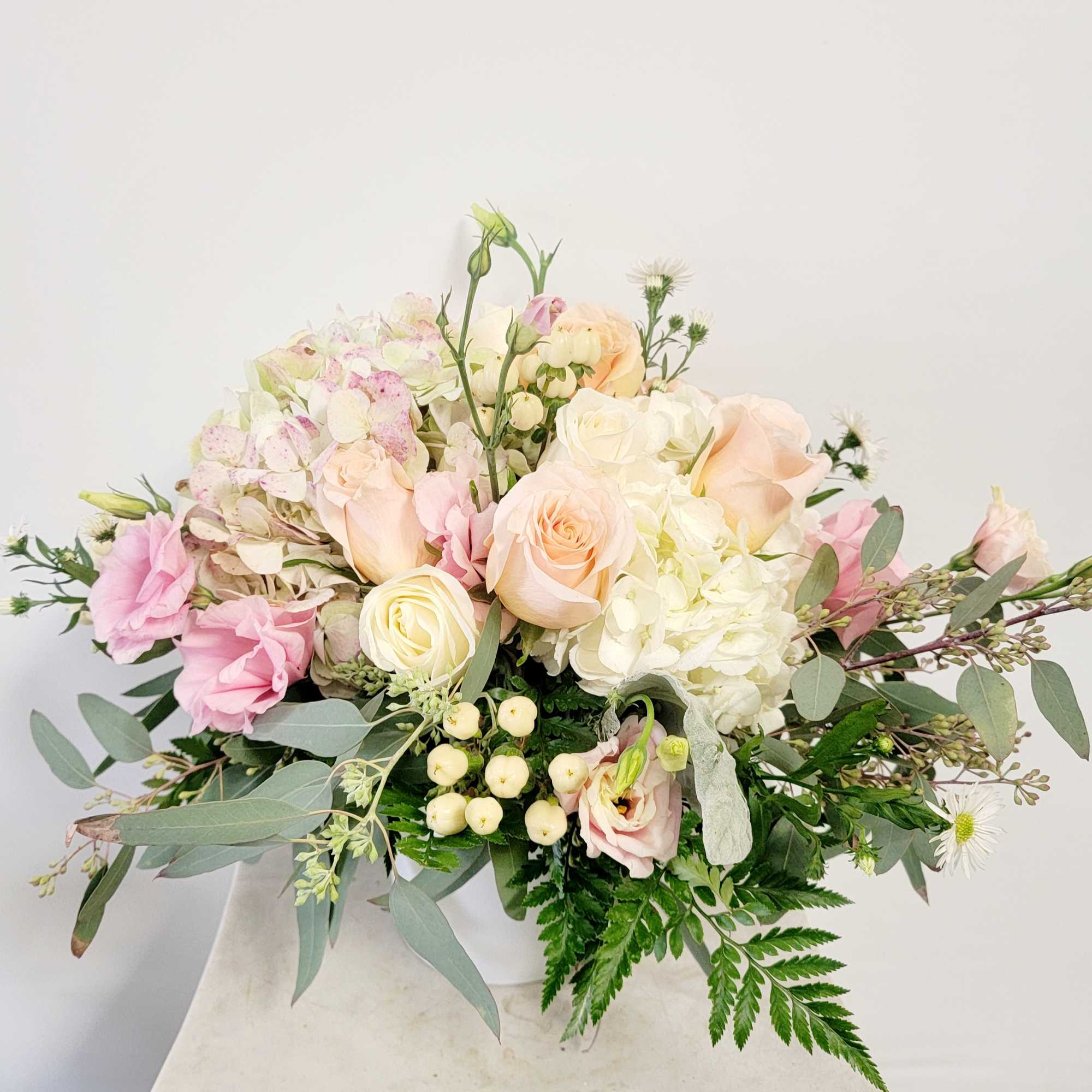 Pastel bouquet of roses, hydrangea, and lisianthus in a white vase