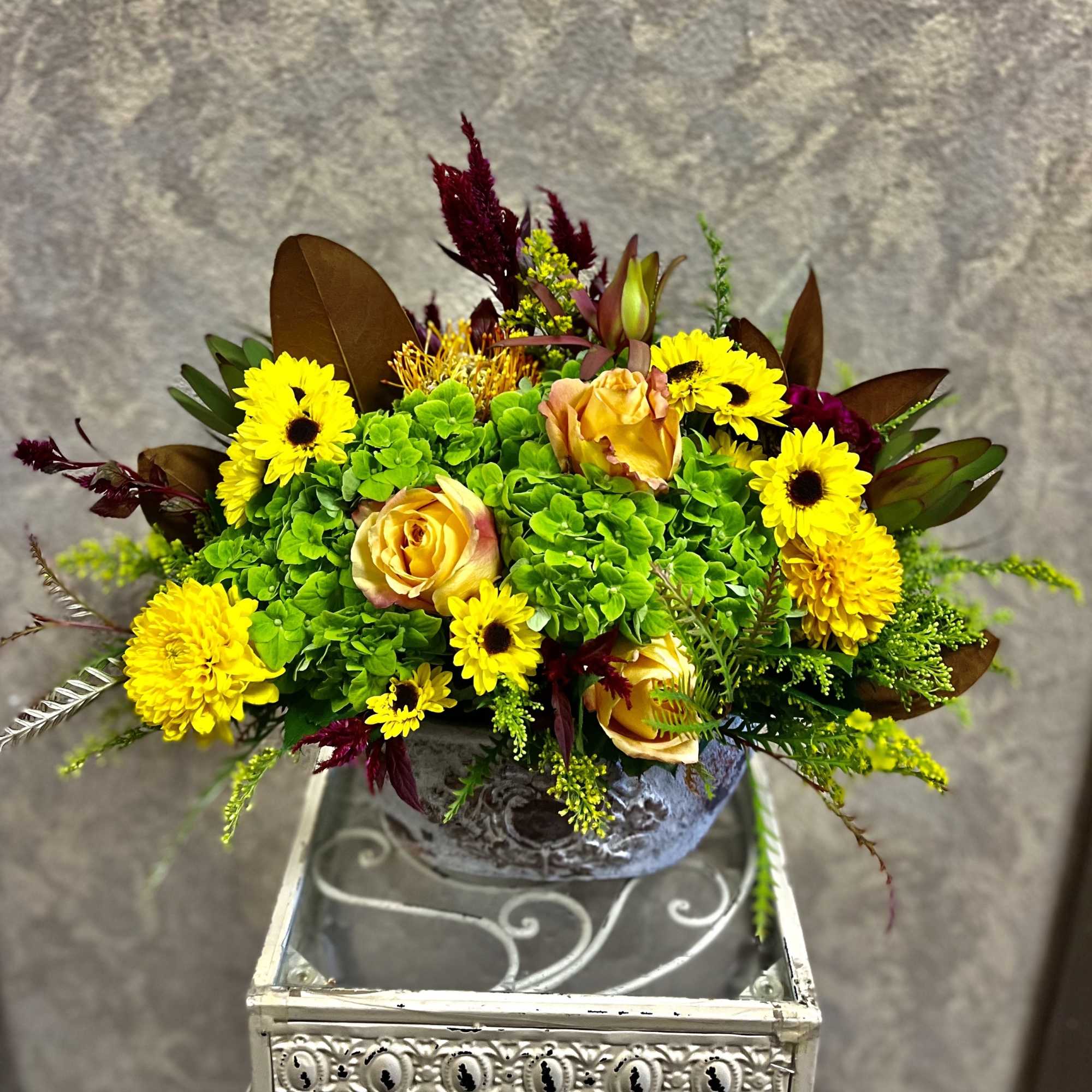 Yellow and peach floral arrangement in a decorative bowl