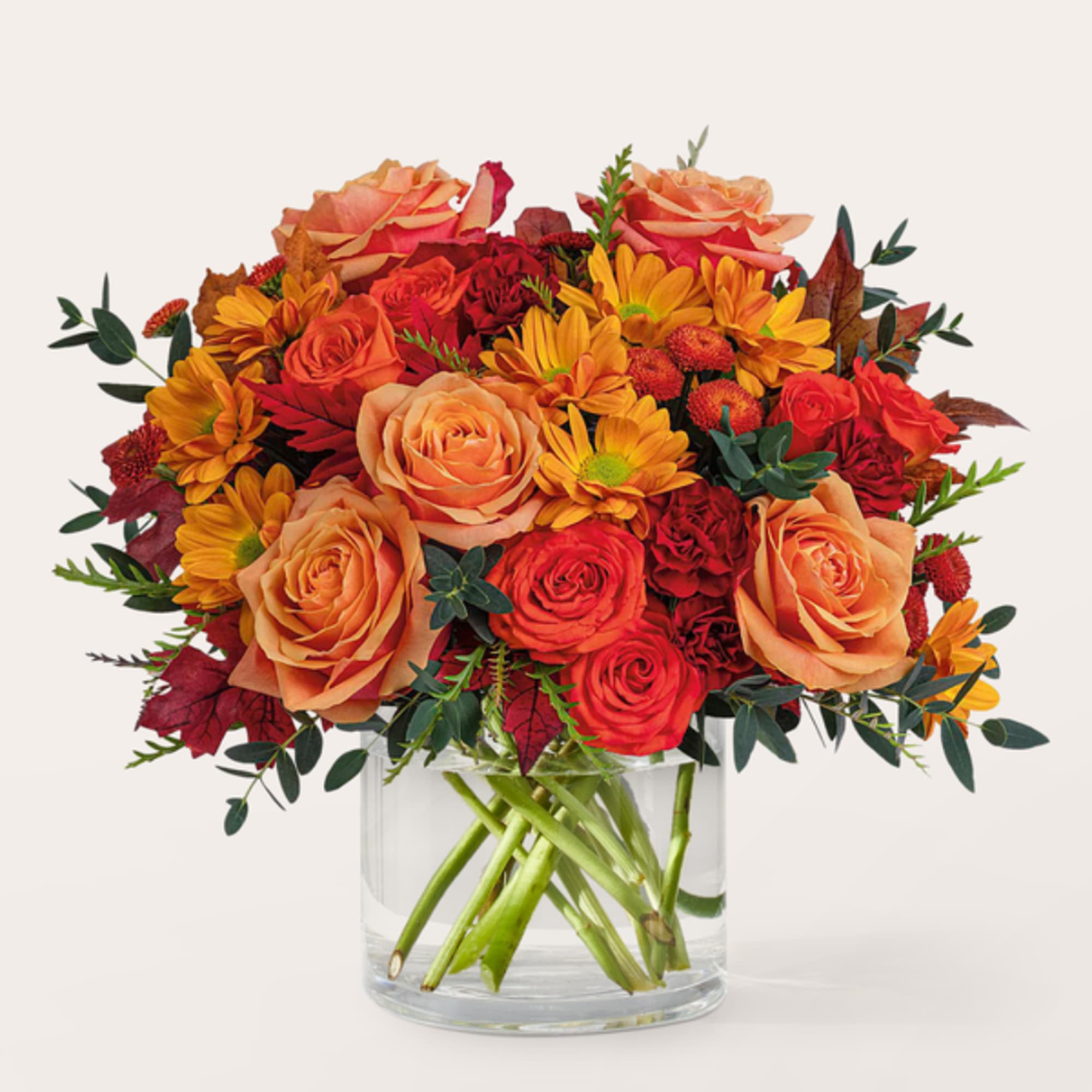 Bouquet of orange and red roses with yellow daisies in a clear glass vase