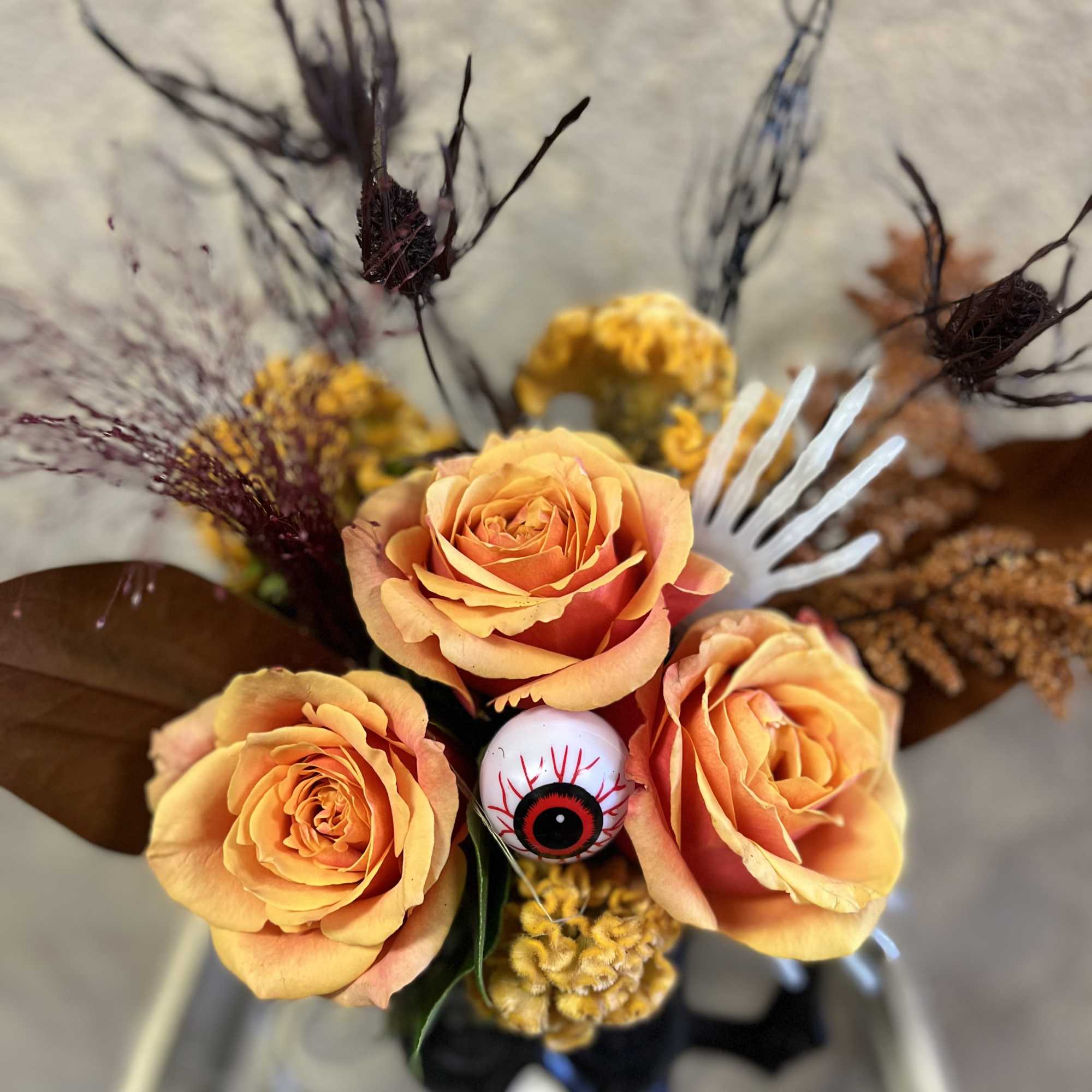 Orange roses in a black vase with Halloween eye decoration