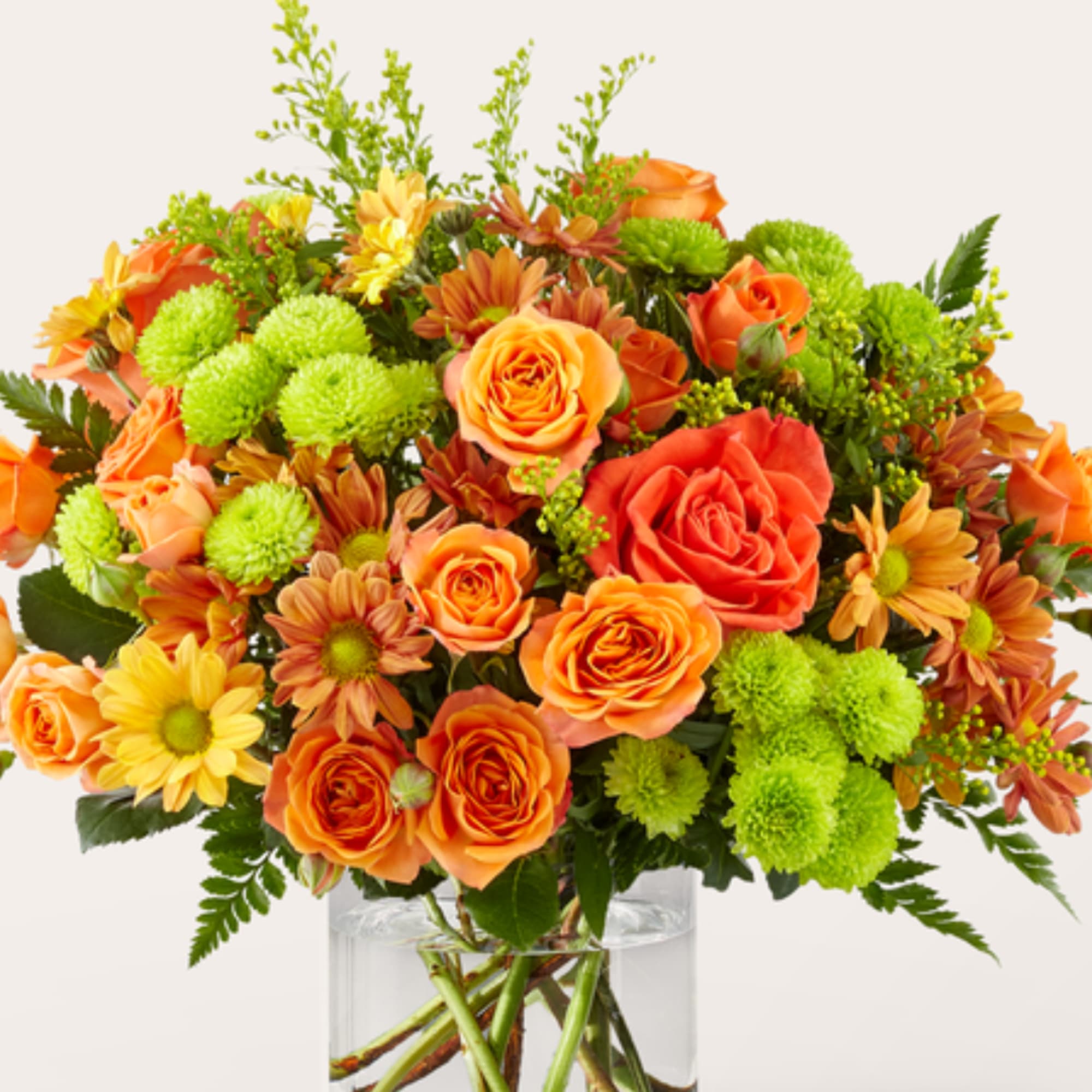 Orange roses and yellow flowers in a clear glass vase