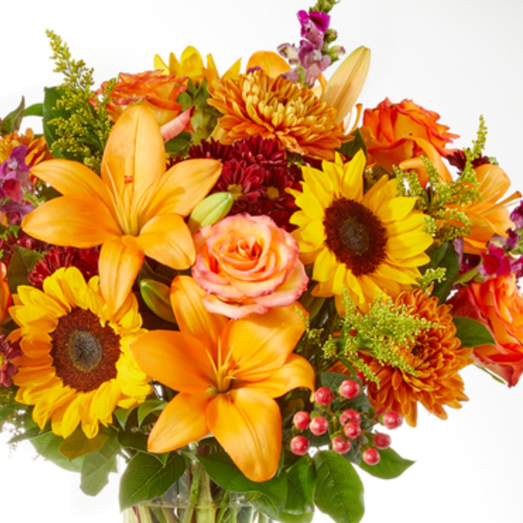 Bright bouquet of orange lilies, sunflowers, and roses in a glass vase