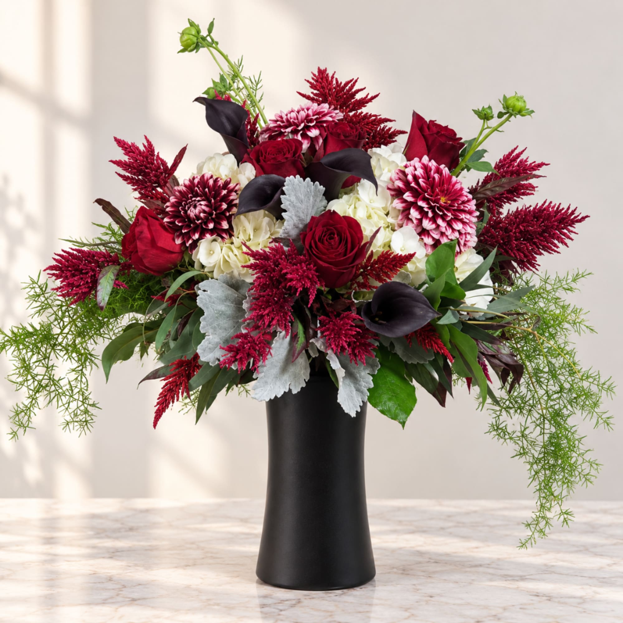 Red and white floral arrangement in a black vase