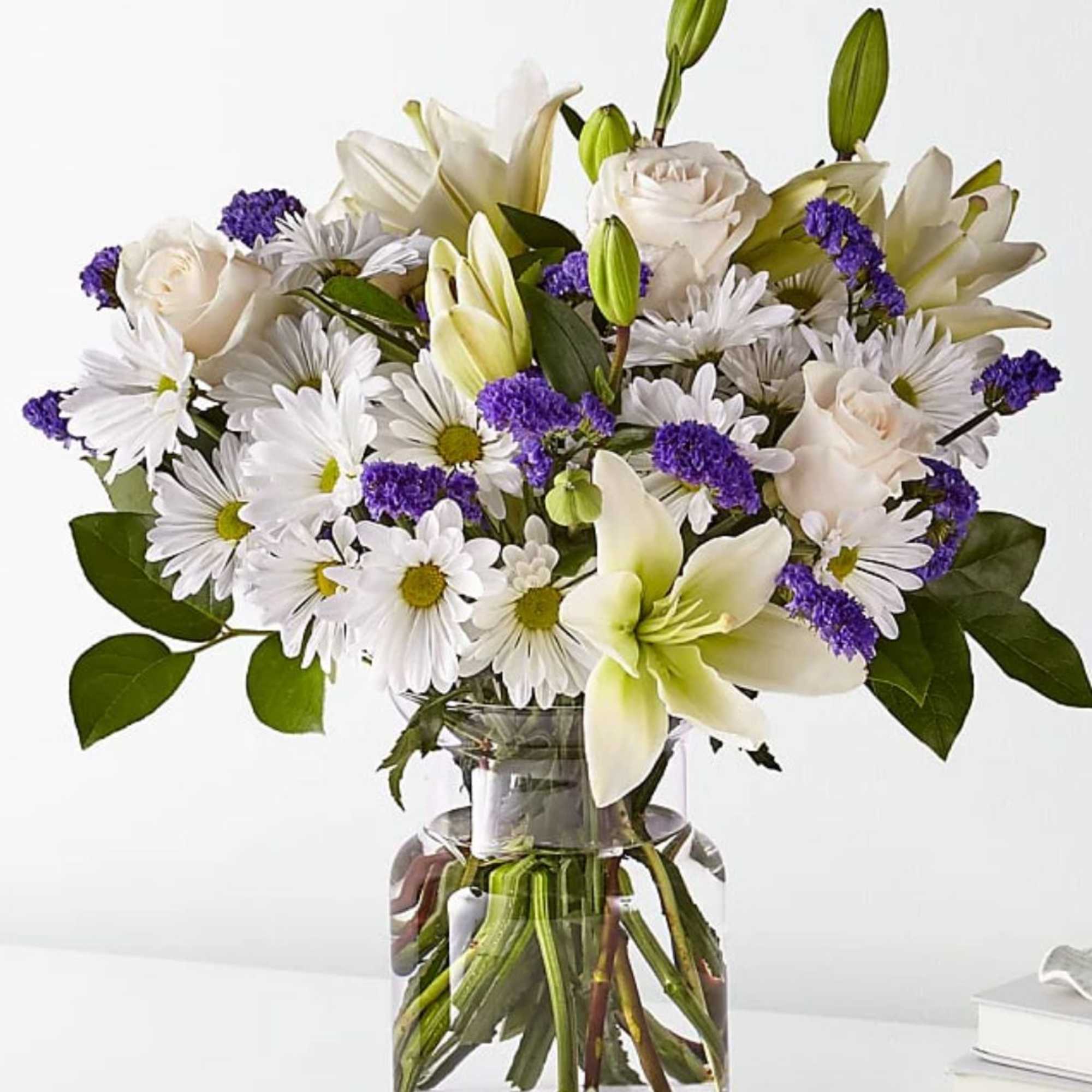 White lilies, roses, and daisies in a glass vase