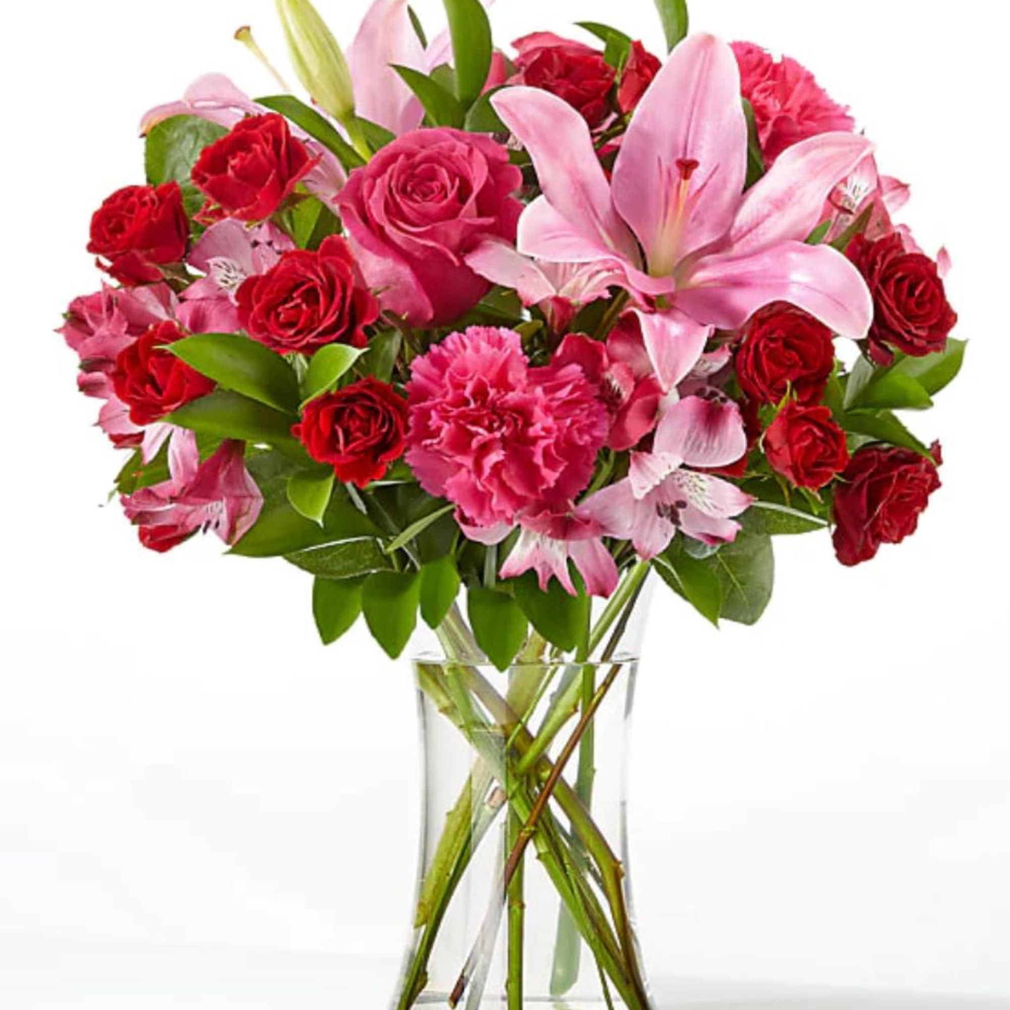 Bouquet of pink lilies, red roses, and carnations in a clear glass vase
