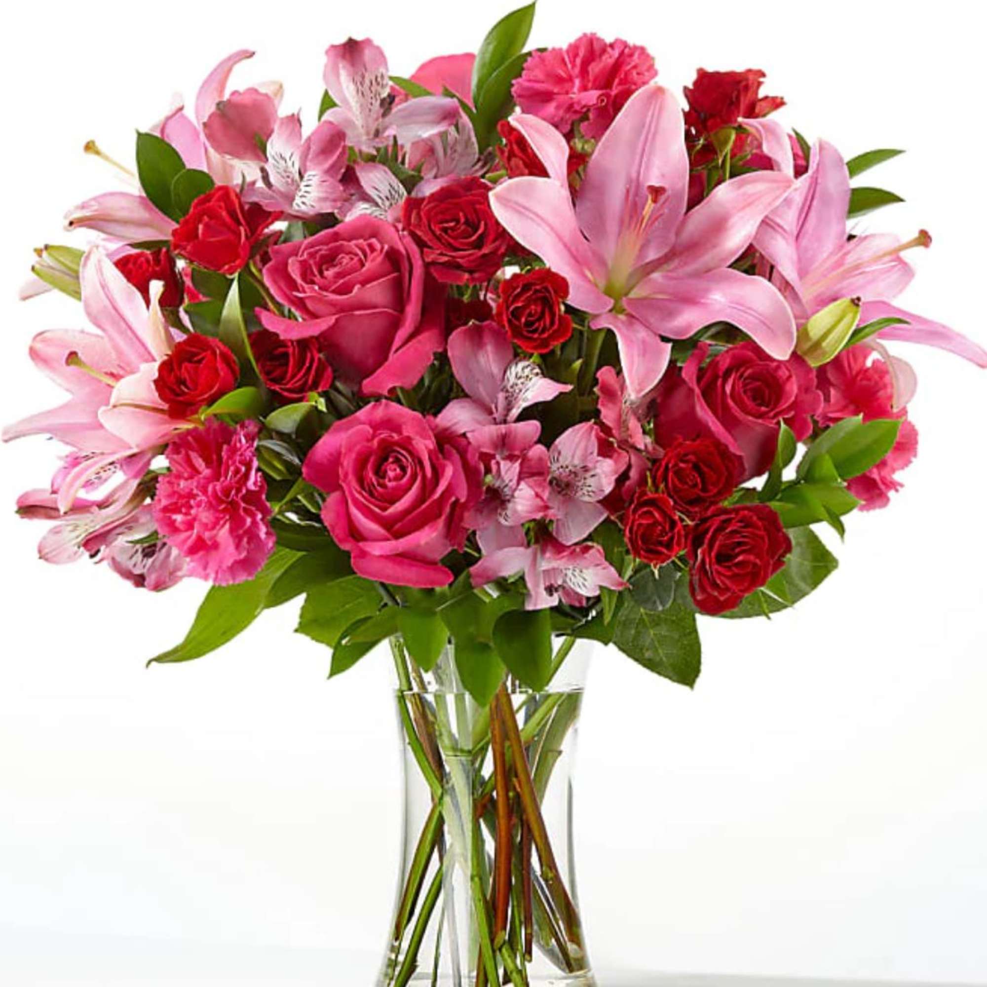Pink lilies and red roses arranged in a clear glass vase