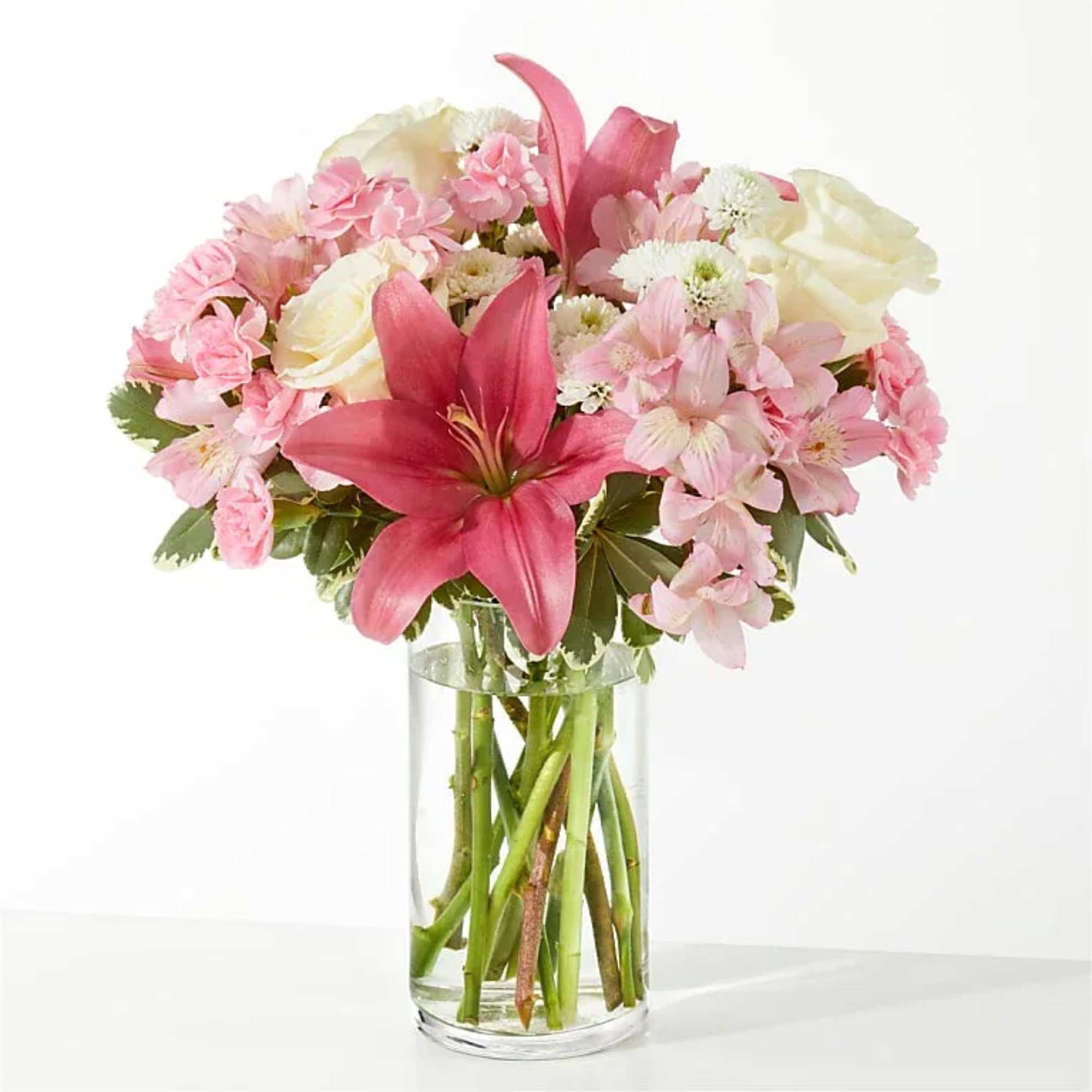Pink and white bouquet with lilies and roses in a clear glass vase