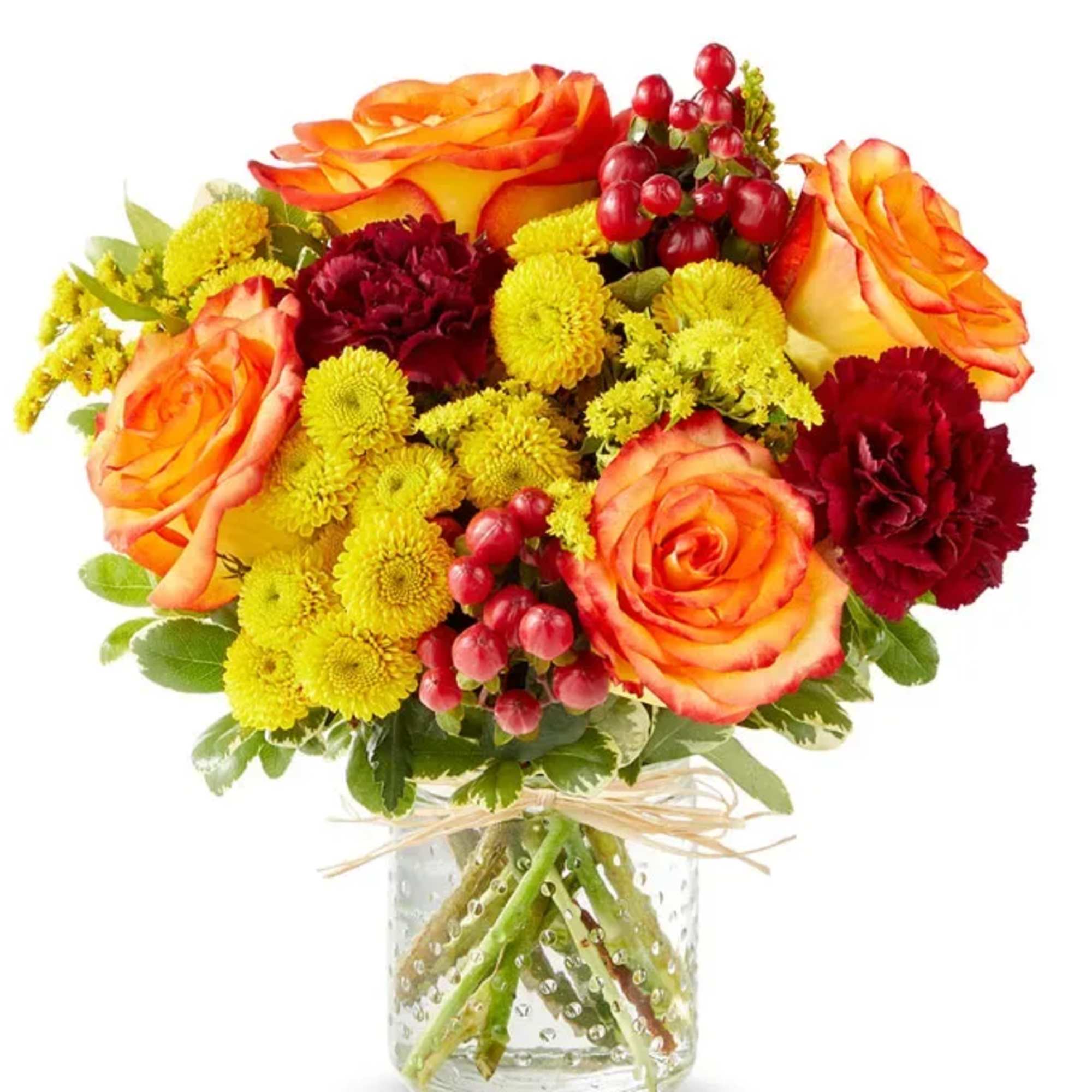 Bouquet of orange roses, yellow mums, and red carnations in a glass vase