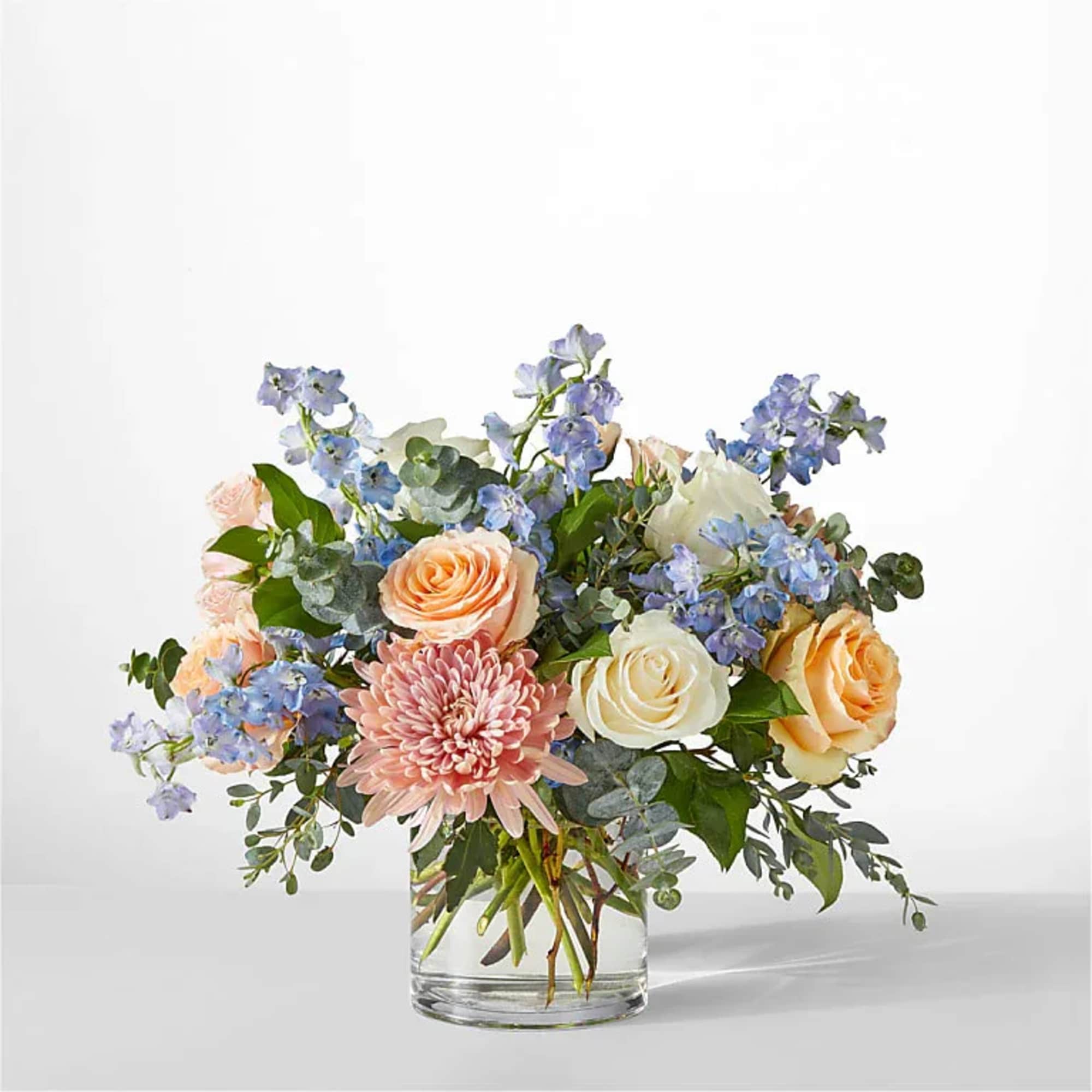 Mixed bouquet of peach and white roses with pink chrysanthemum in a glass vase