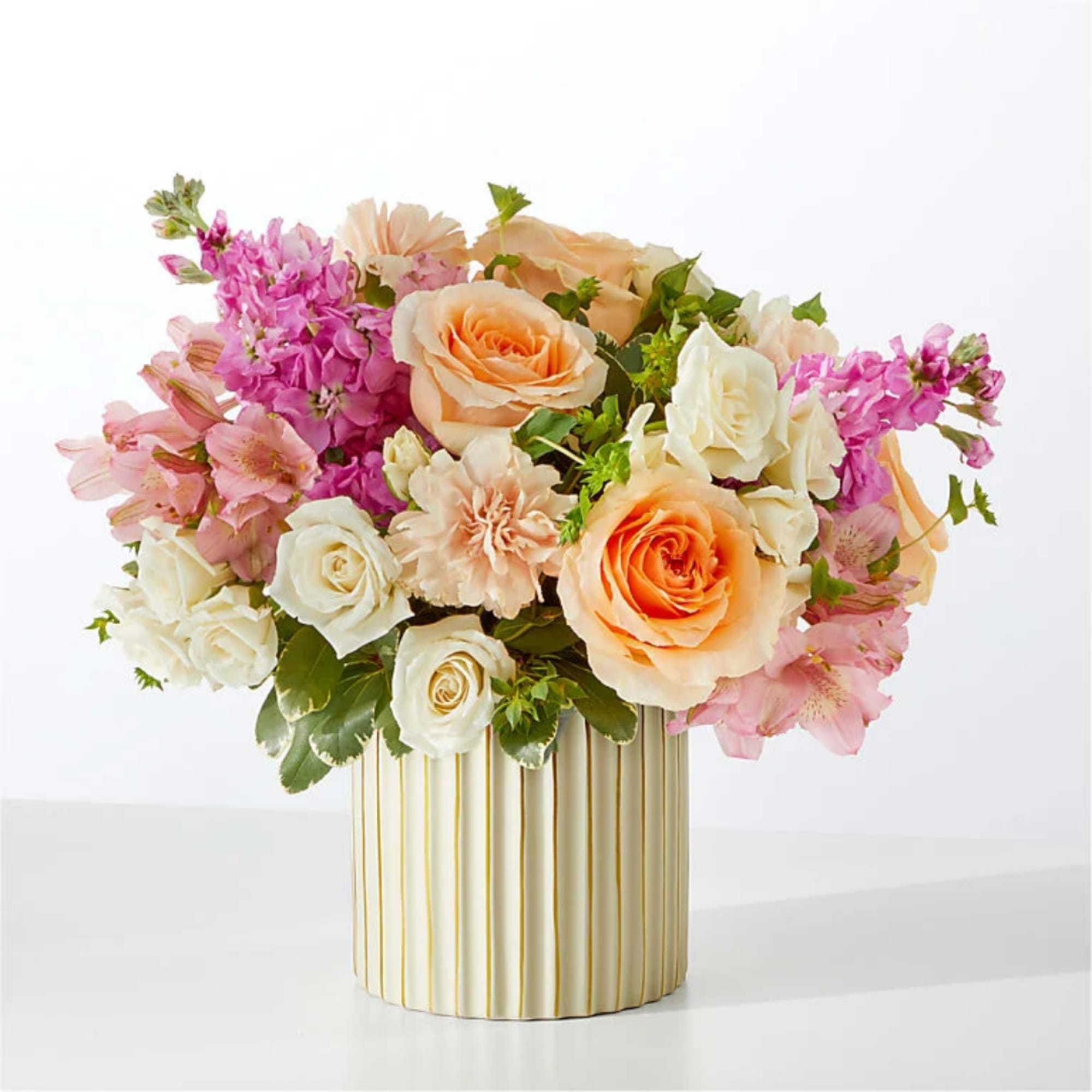 Peach and pink roses with white blooms in a striped vase