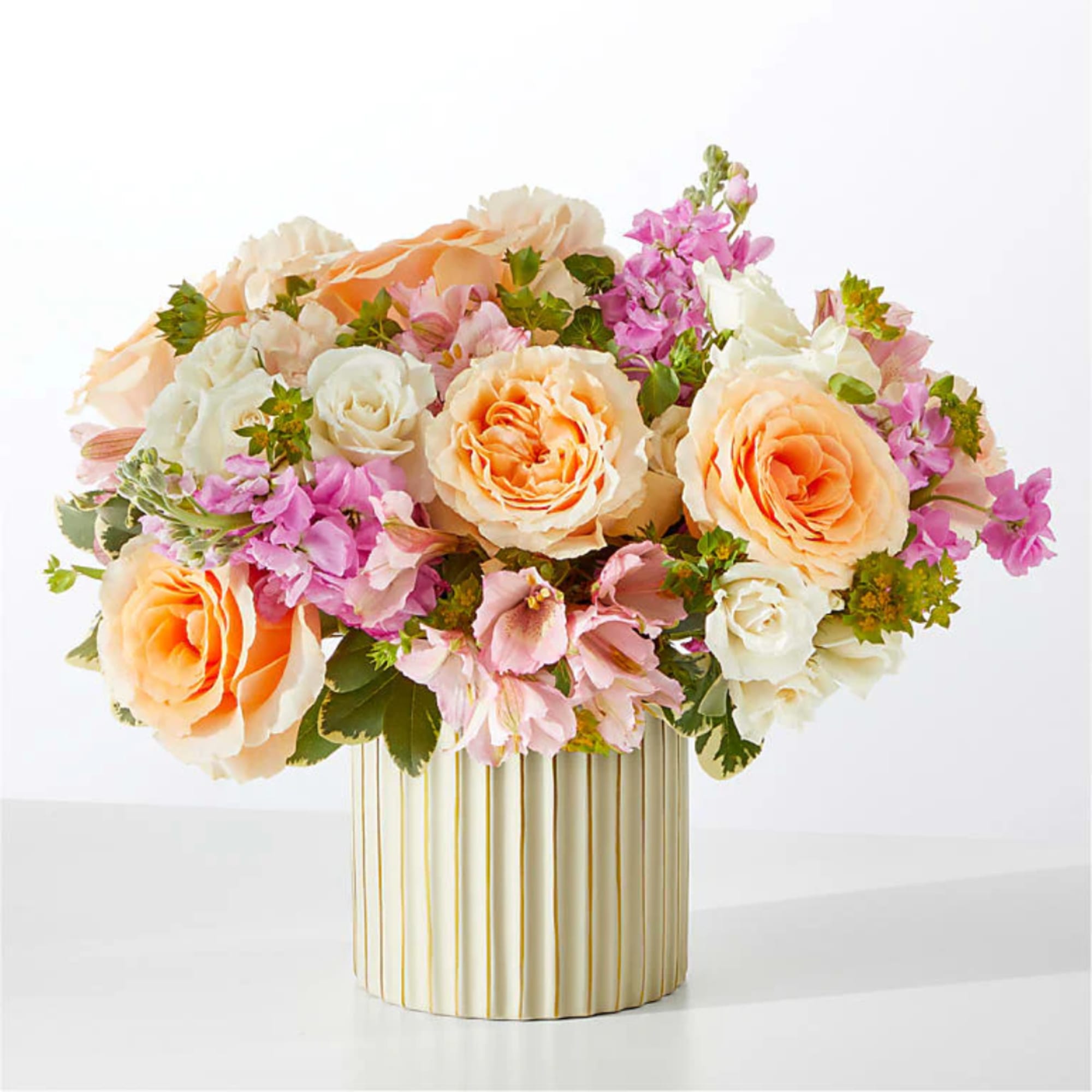 Peach and white roses with pink flowers in a striped vase