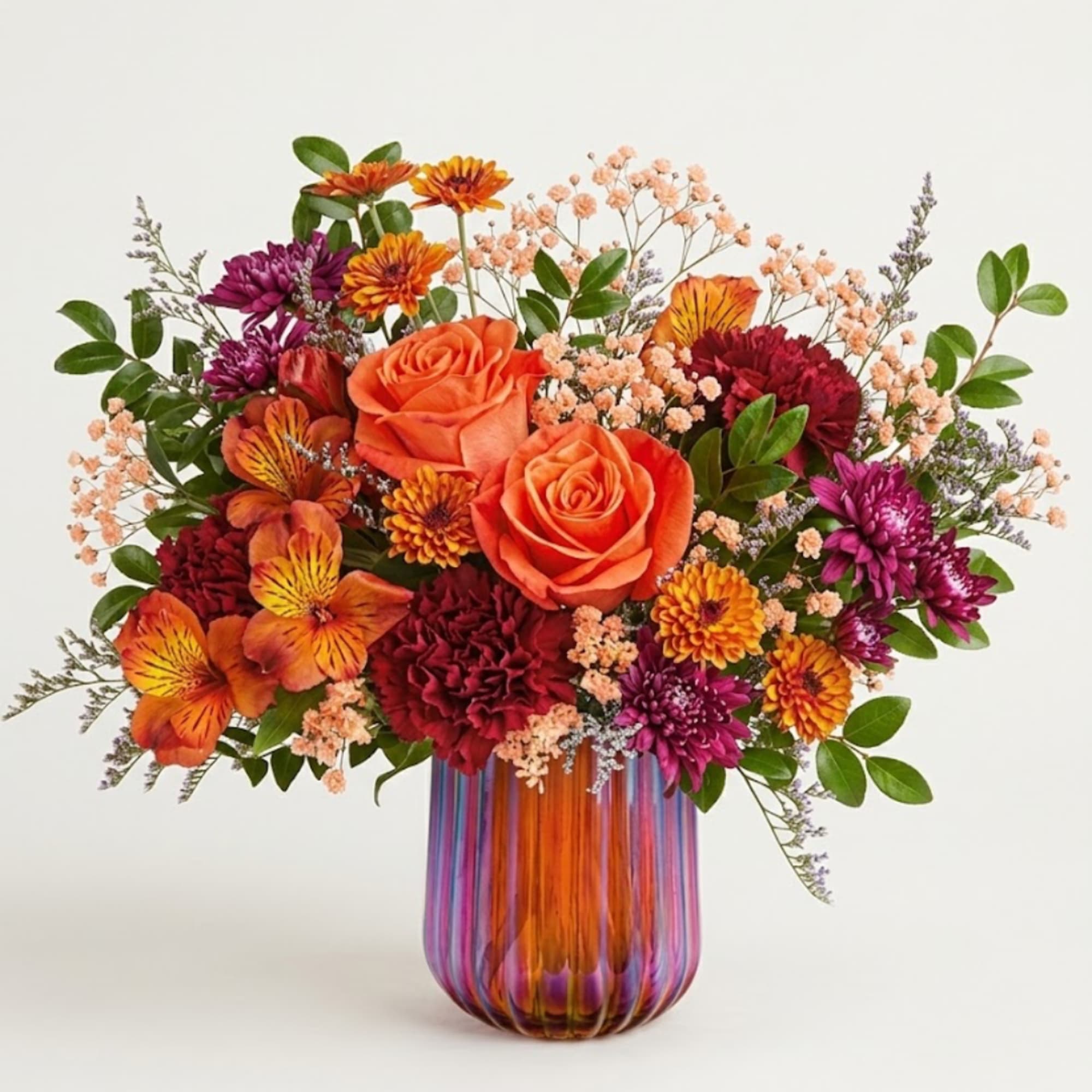 Orange roses and mixed blooms in a striped glass vase