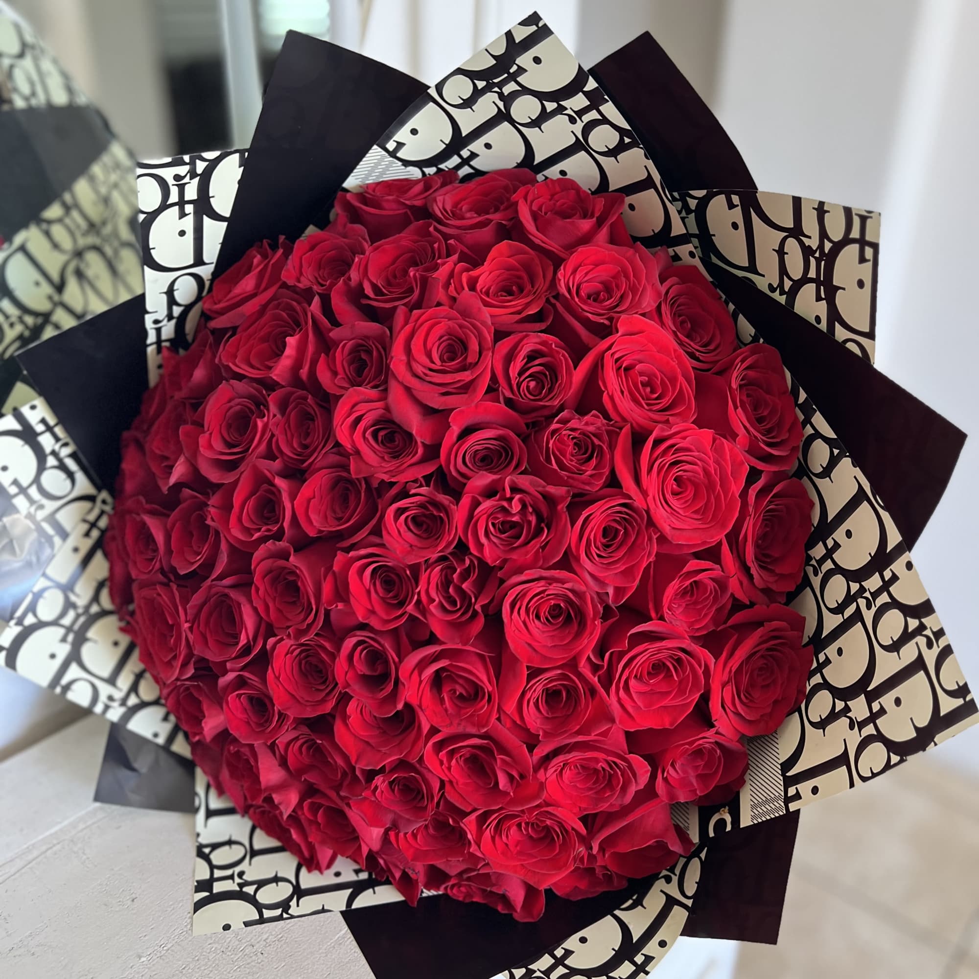 Large bouquet of red roses wrapped in black-and-white paper