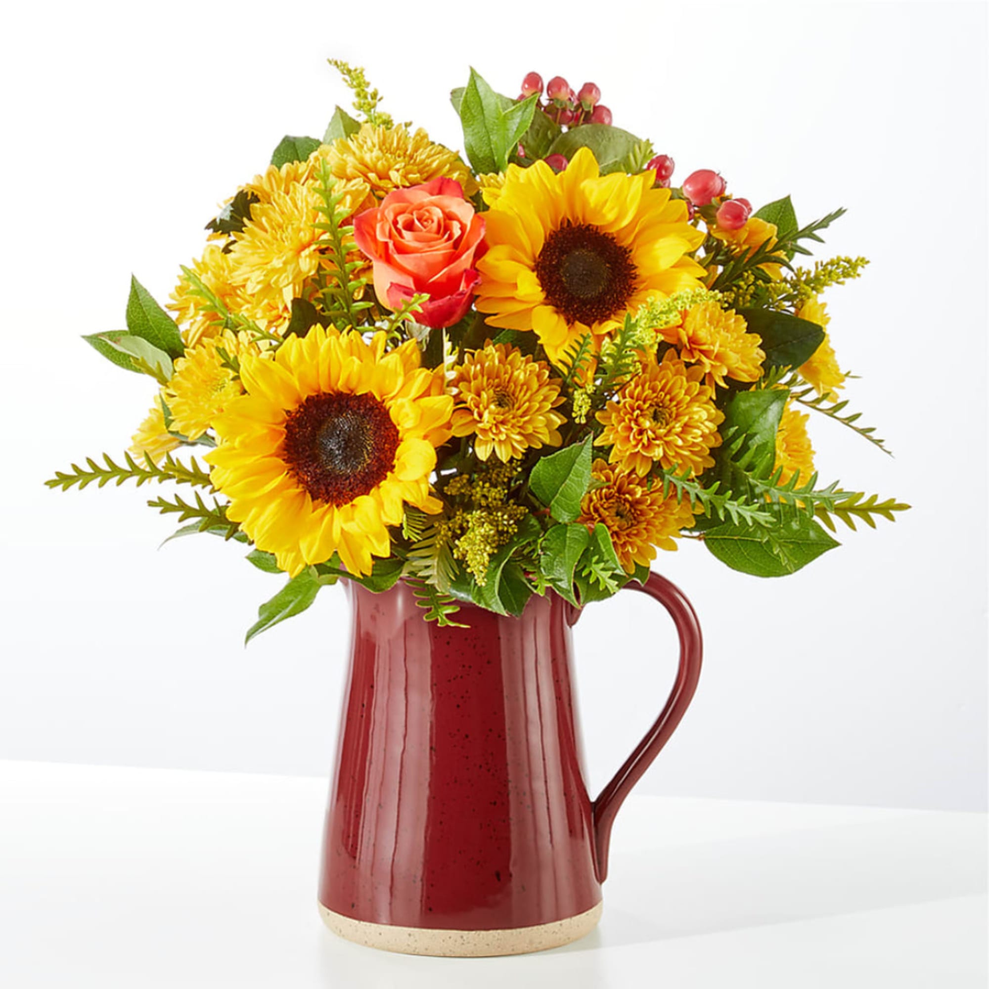 Sunflowers and orange roses arranged in a red pitcher vase