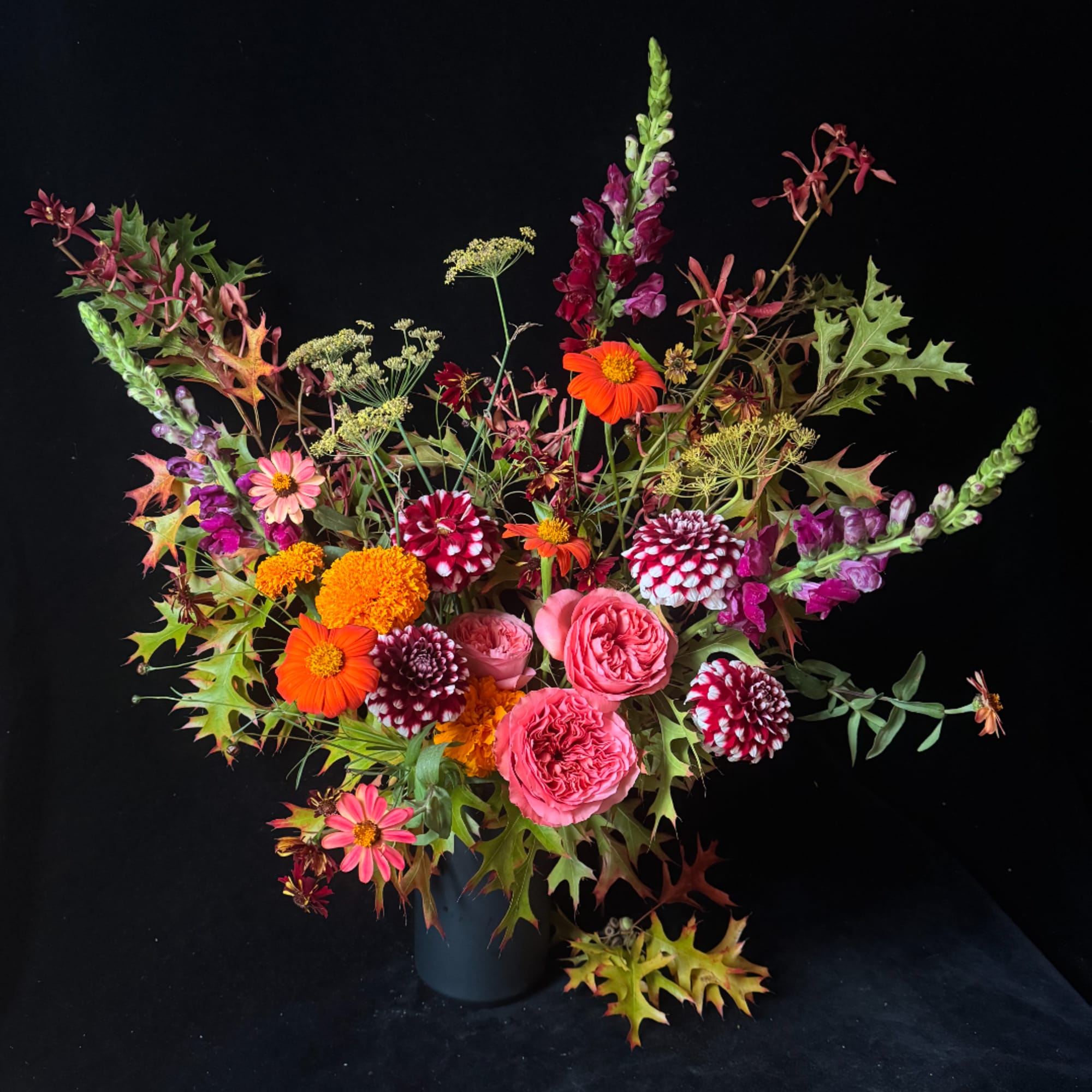 Mixed bouquet in a dark vase with pink, orange, and burgundy flowers