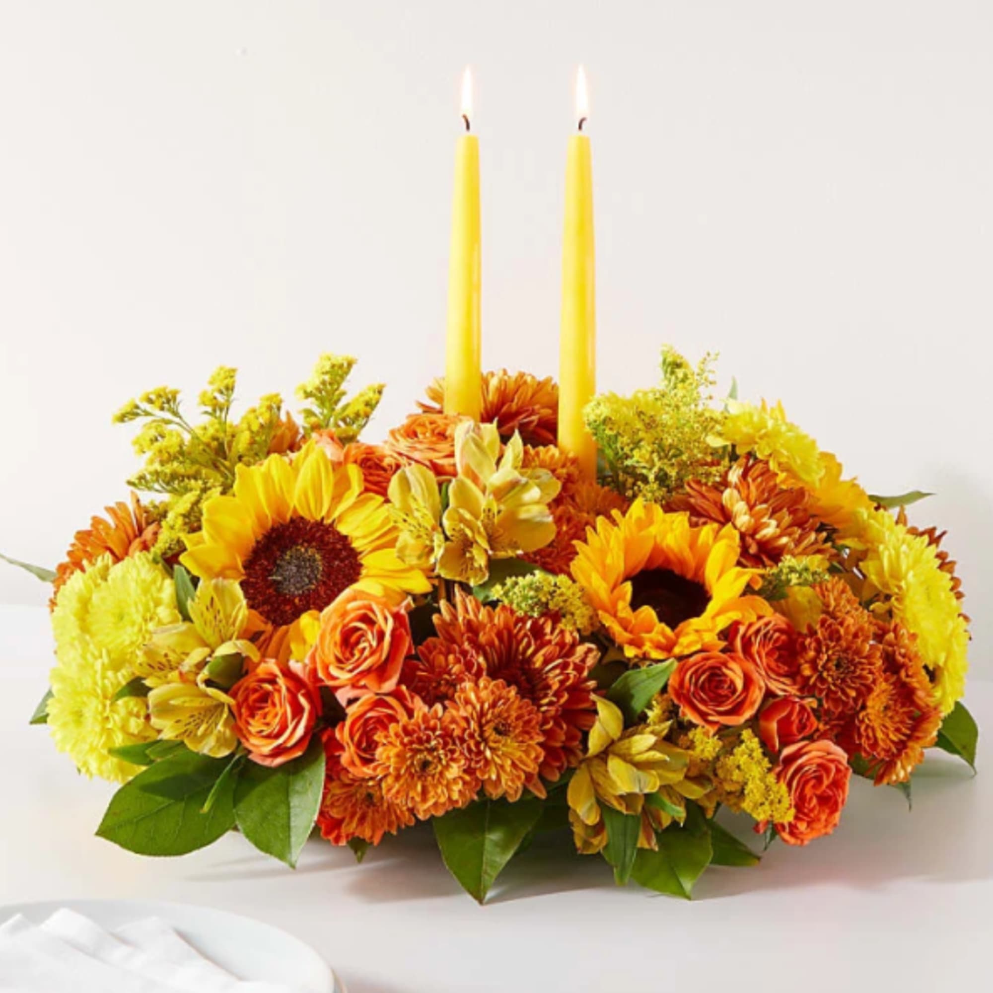 Yellow and orange floral centerpiece with two tall candles