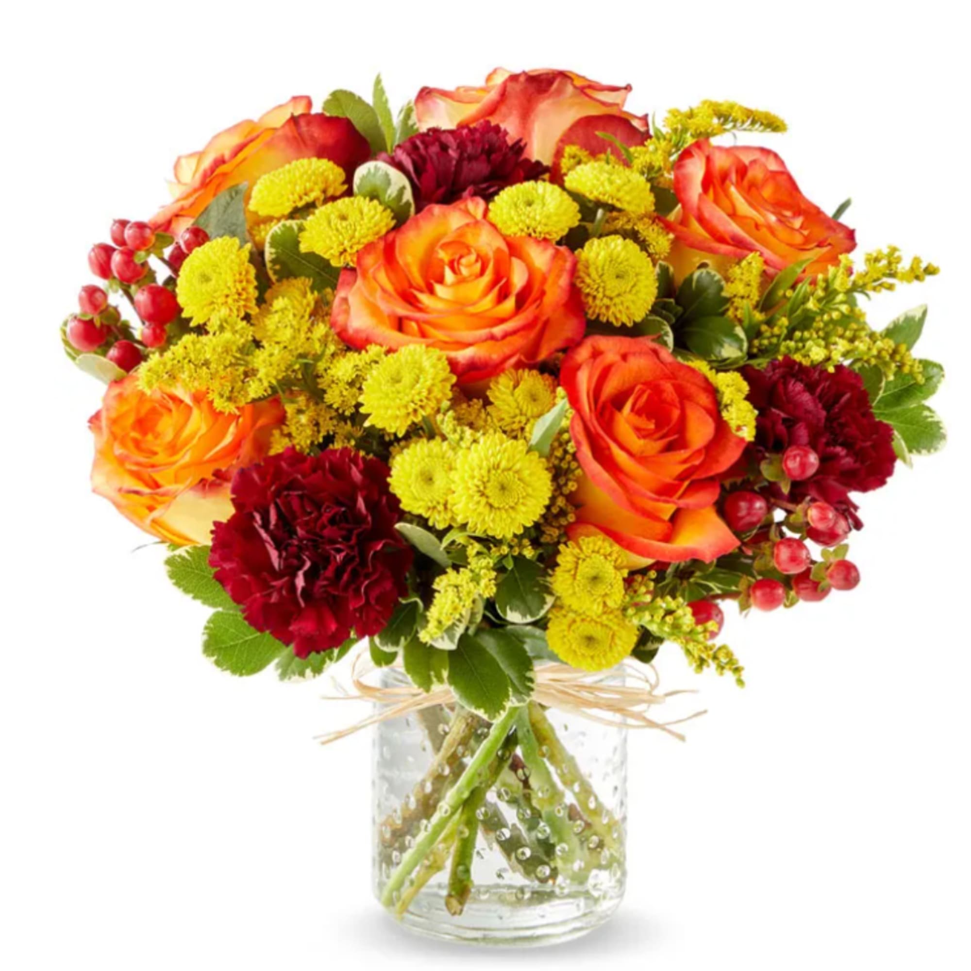 Bouquet of orange roses and red carnations in a clear glass vase