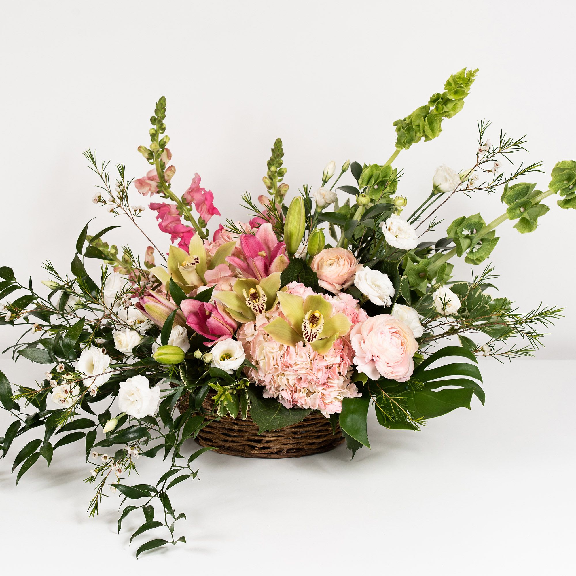 Basket arrangement of pink and white flowers with tall green spikes