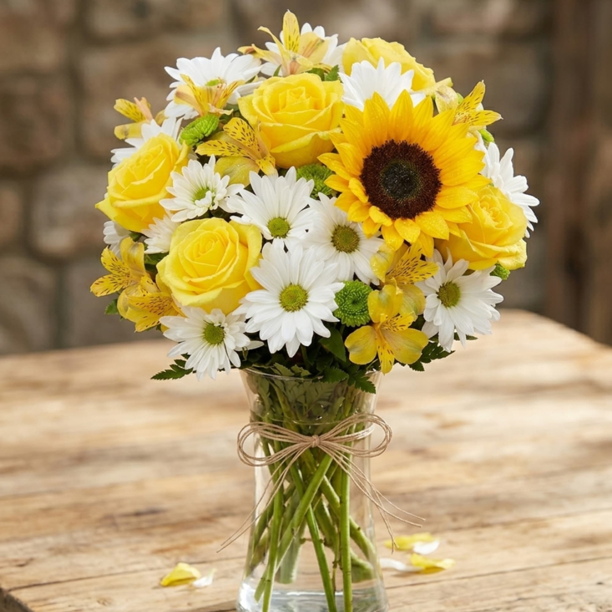 Yellow roses and white daisies in a clear glass vase