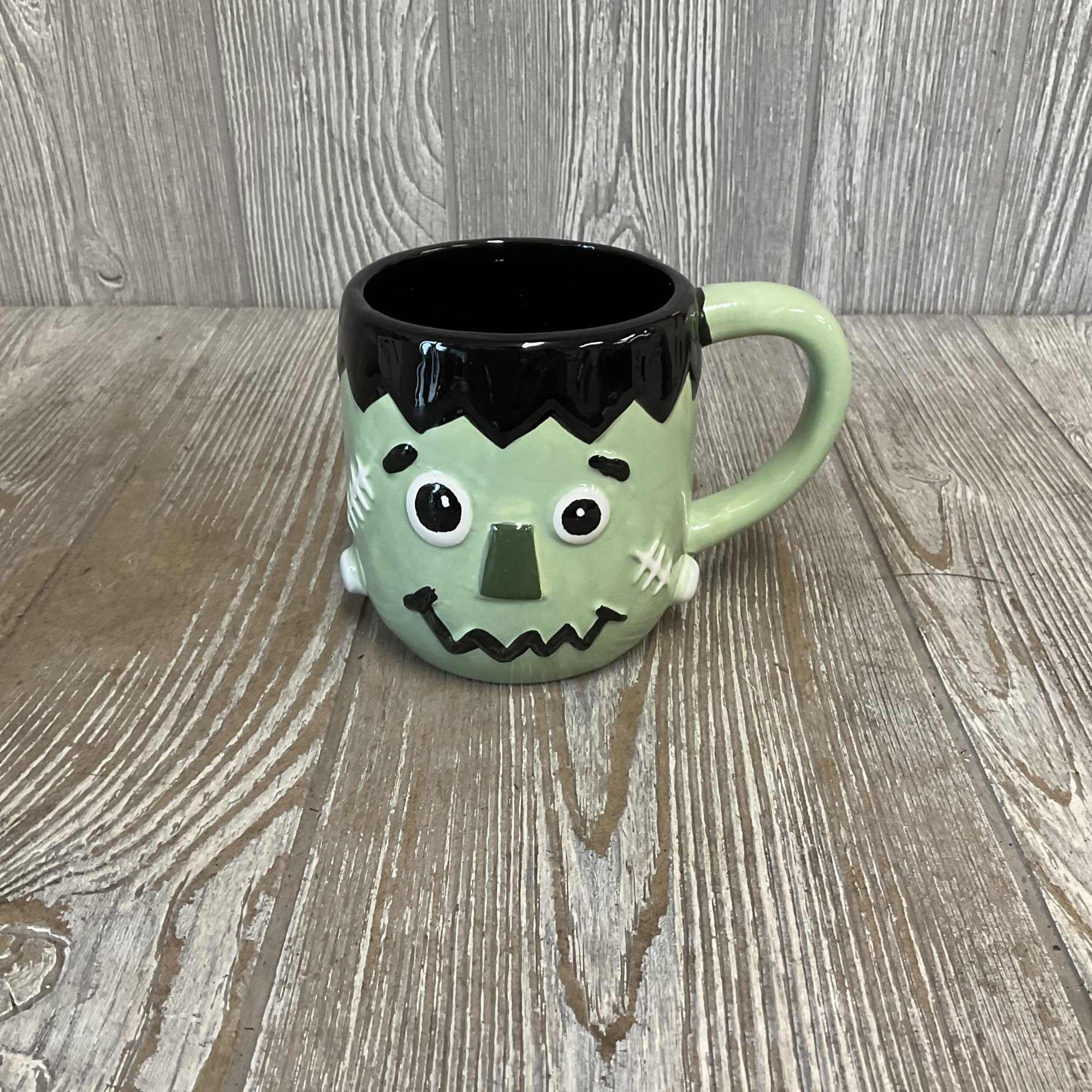 Frankenstein face mug with a black rim and green handle