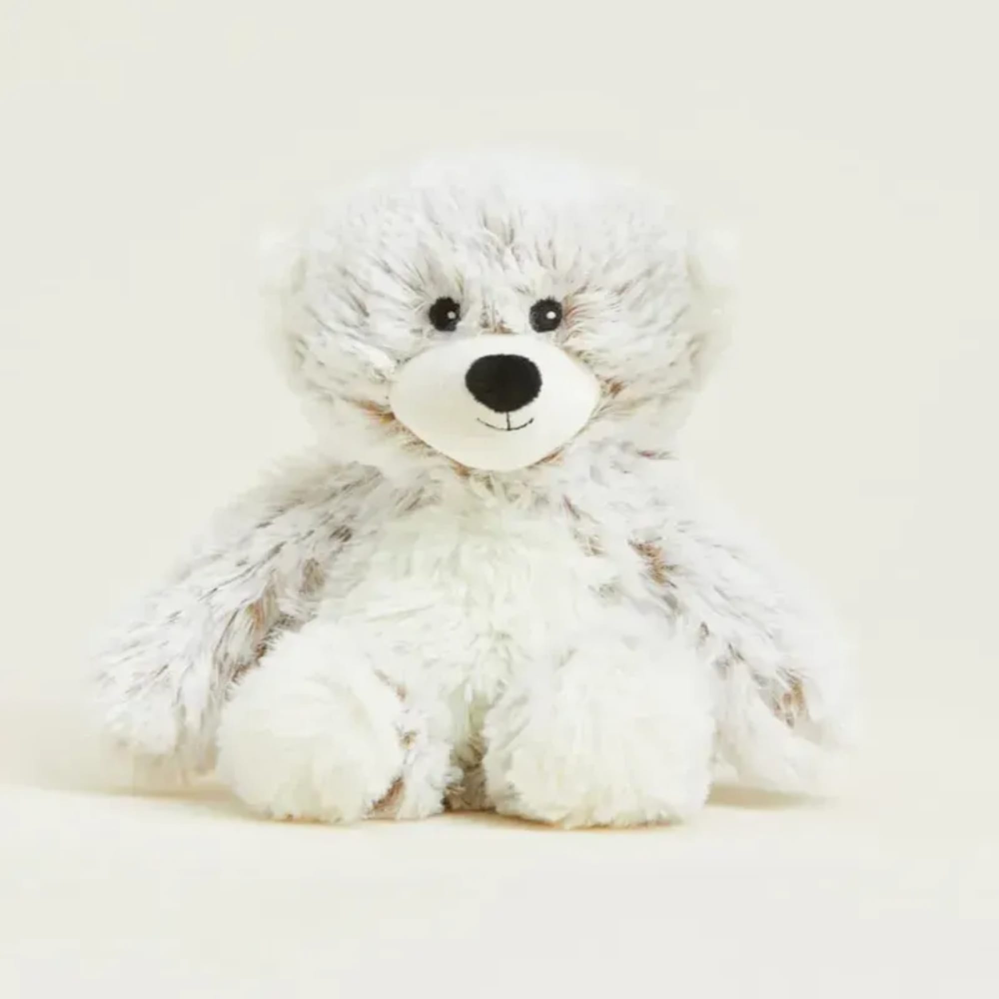 White plush teddy bear with black eyes and nose on a plain background