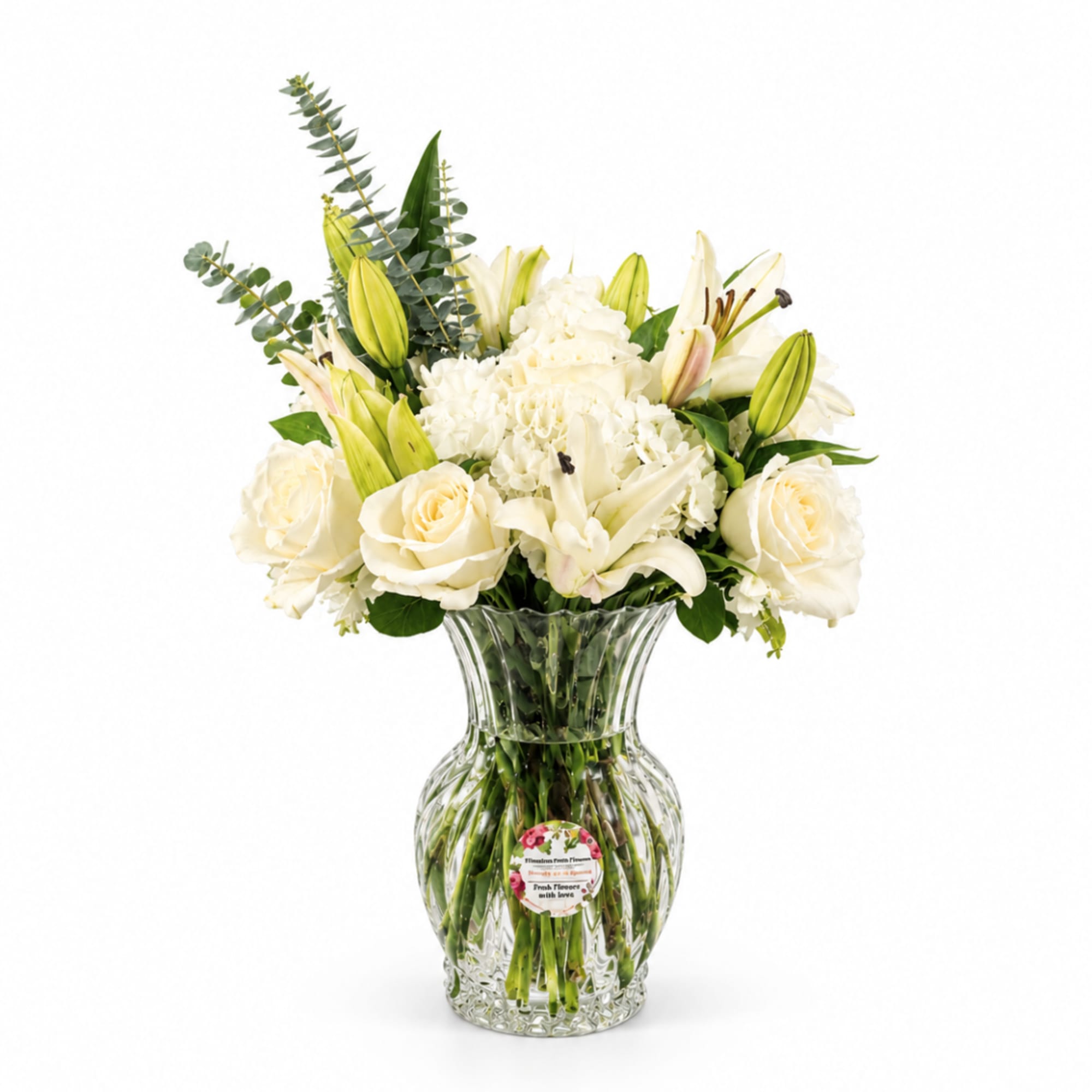 White lilies and roses arranged in a clear glass vase