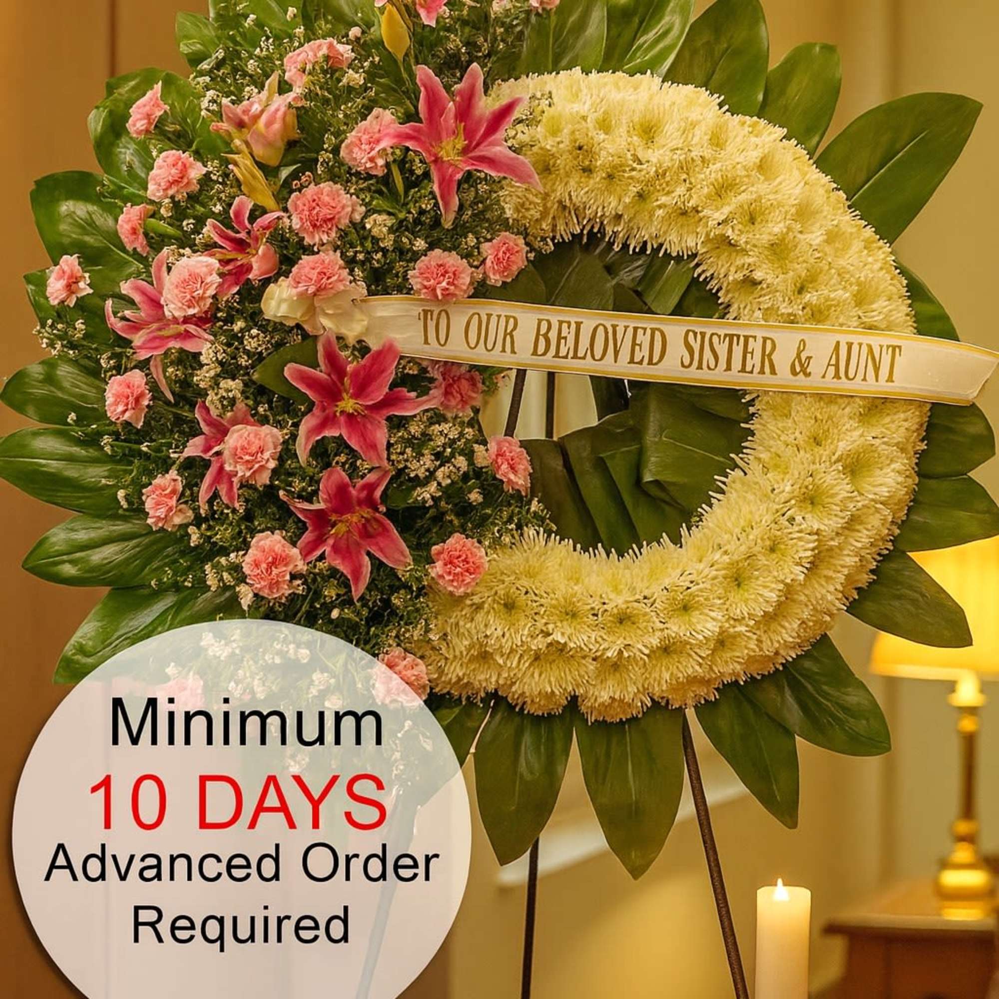 Standing sympathy wreath with white ring and pink lilies and carnations on a tripod stand