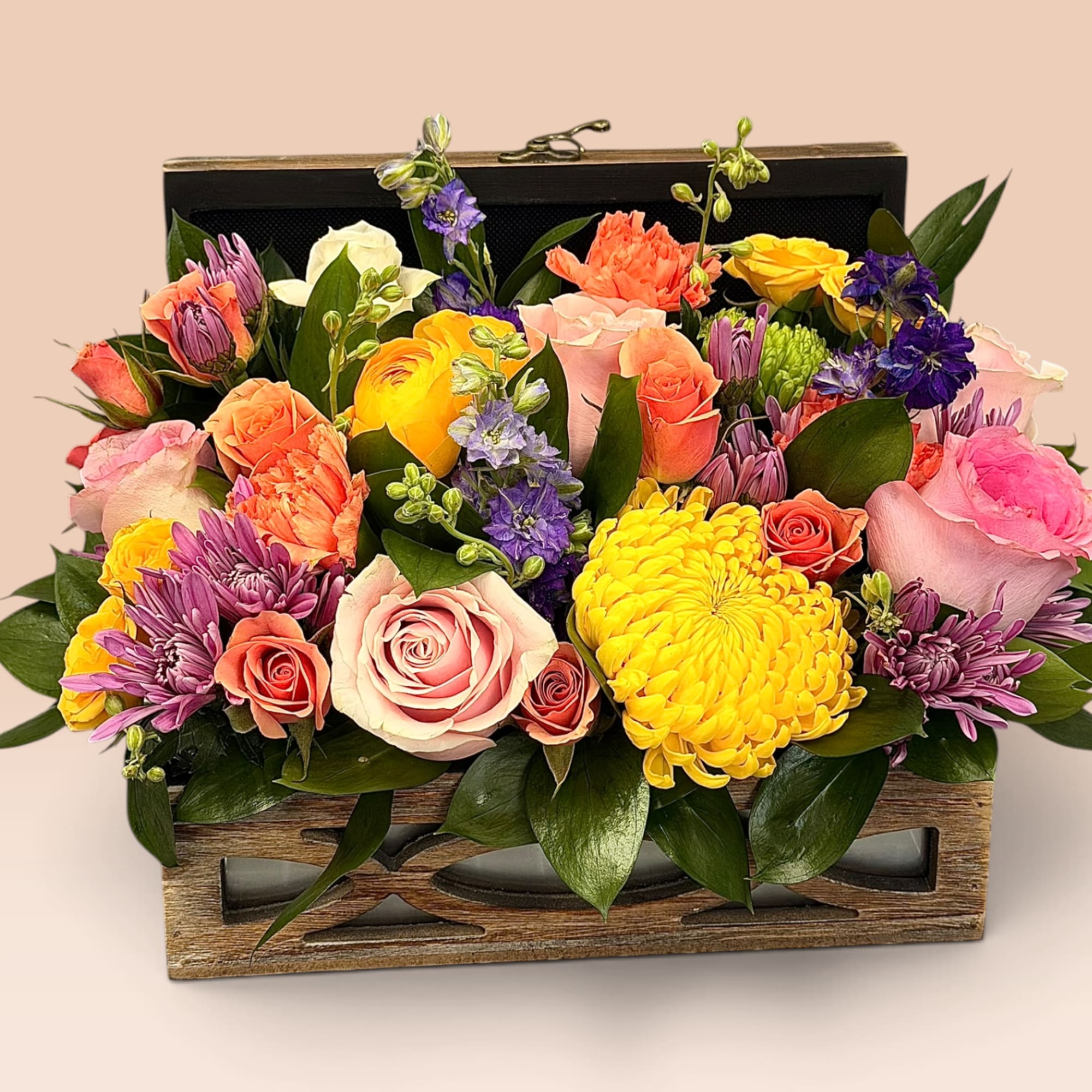 Mixed bouquet in a wooden box with pink, yellow, and purple blooms