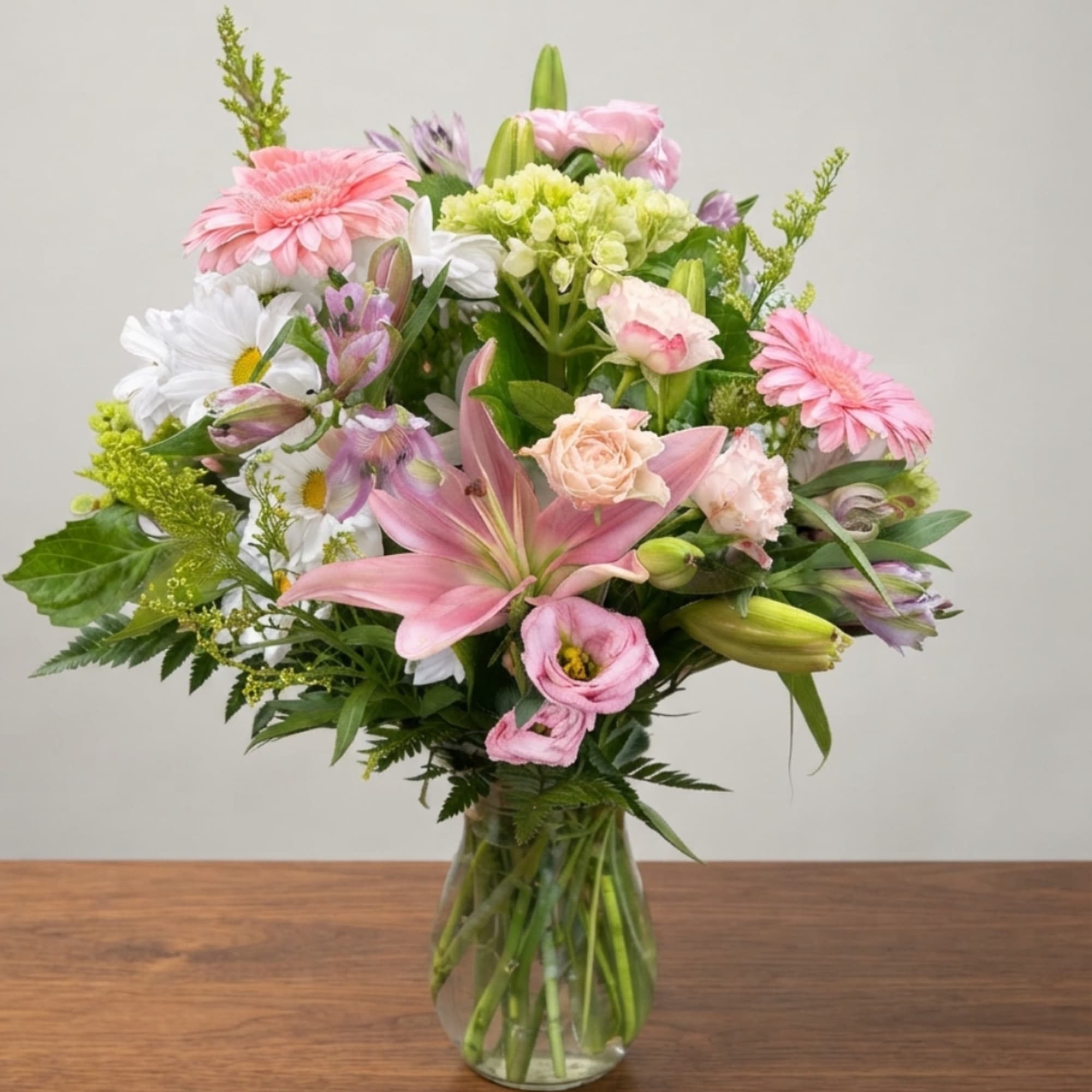 Mixed pink and white flowers arranged in a clear glass vase