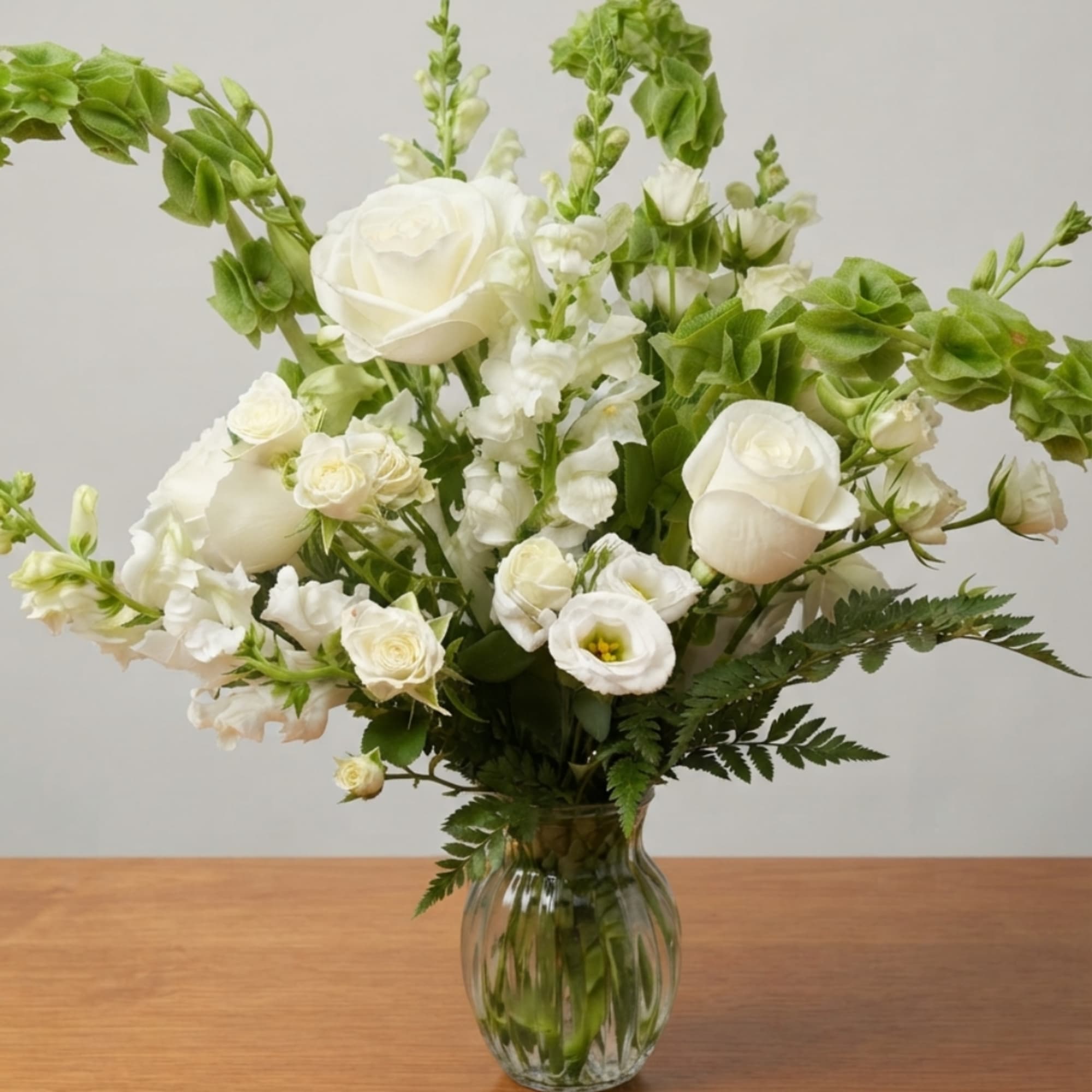 White roses and small white blooms in a clear glass vase