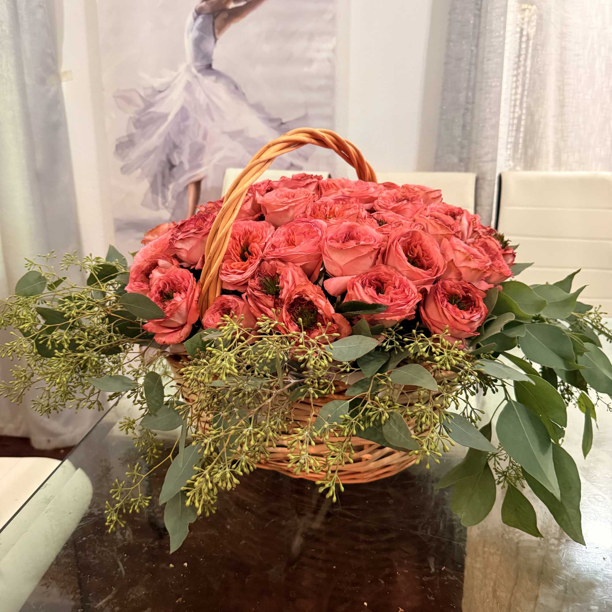 Basket of pink roses with greenery on a table
