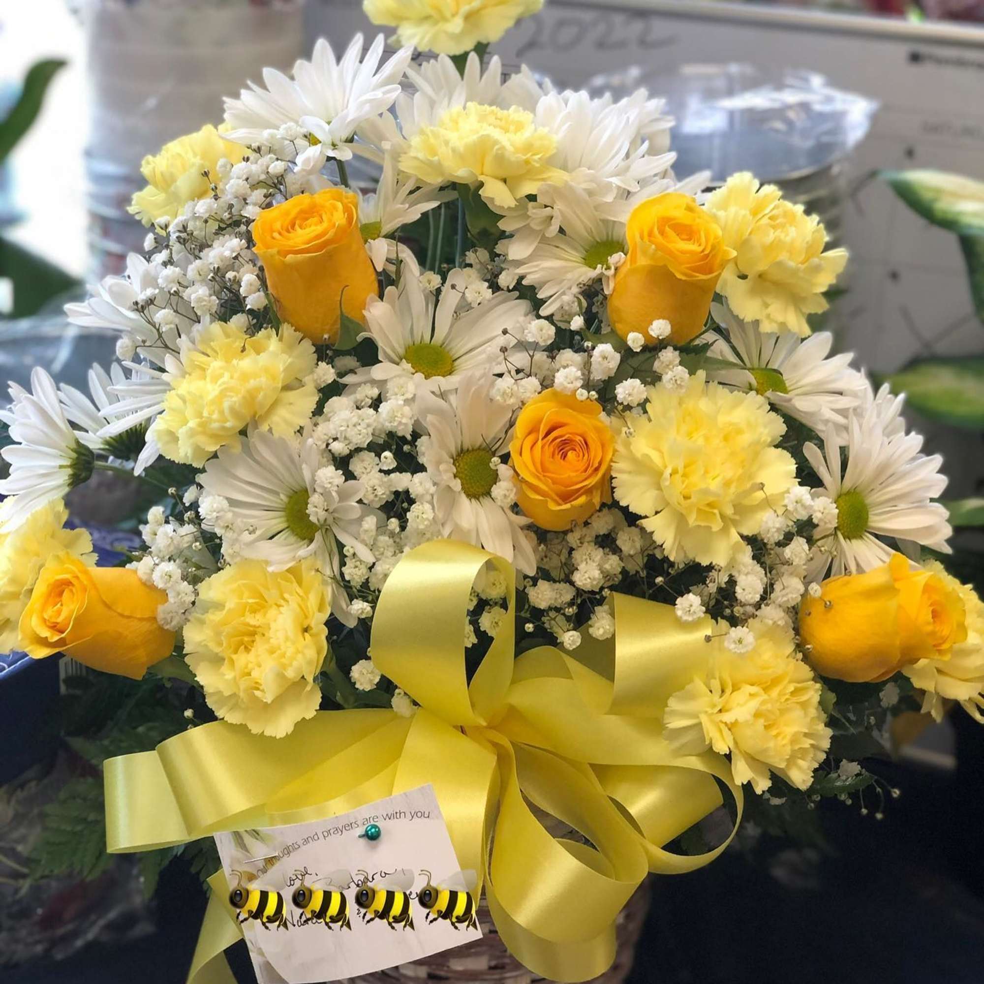 Yellow roses and white daisies in a basket with a yellow ribbon