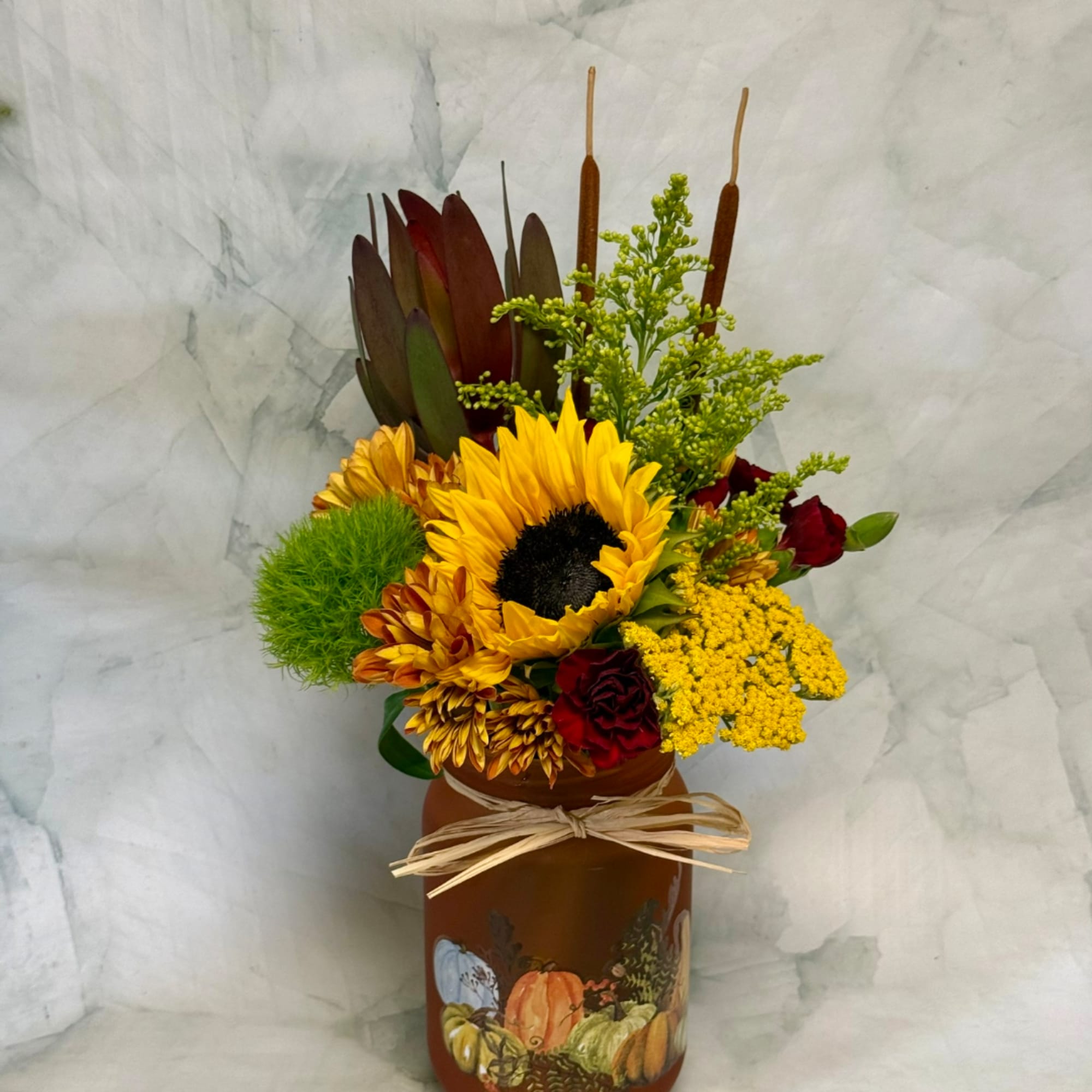 Sunflower arrangement in a painted brown jar with yellow and red flowers