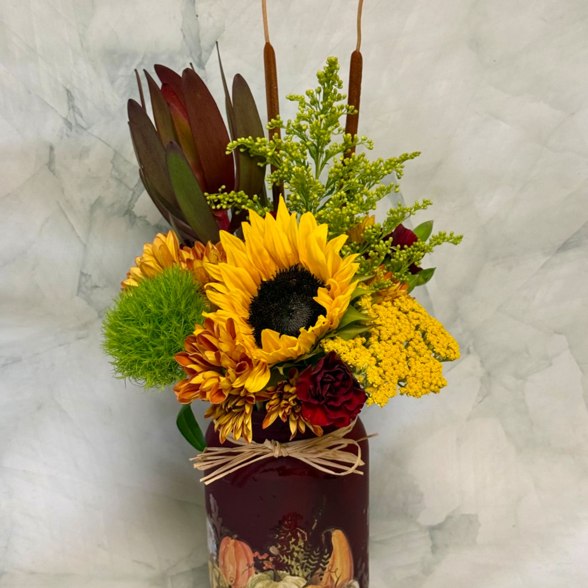 Sunflower arrangement in a burgundy vase with yellow and red blooms