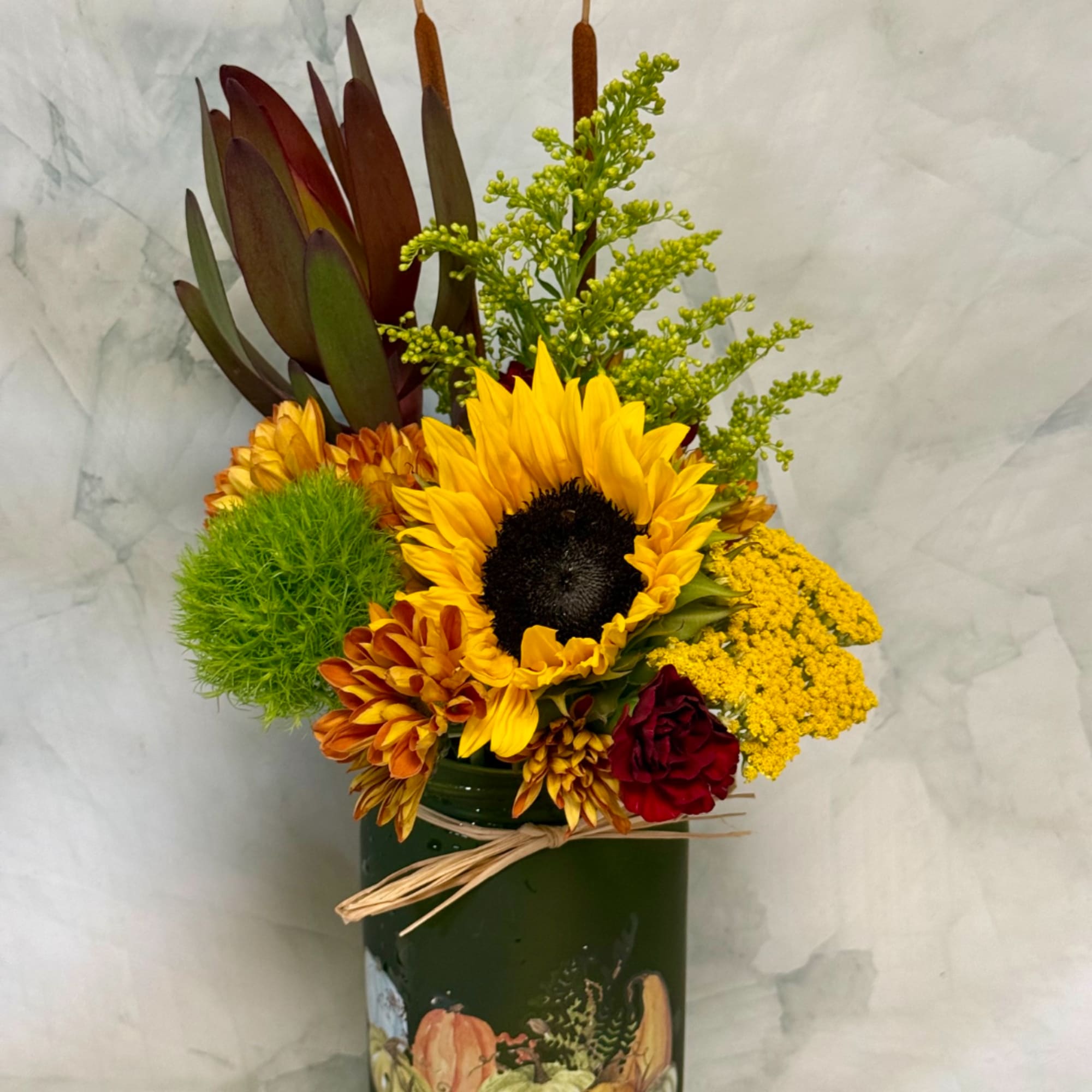 Sunflower arrangement in a green painted vase with mixed blooms