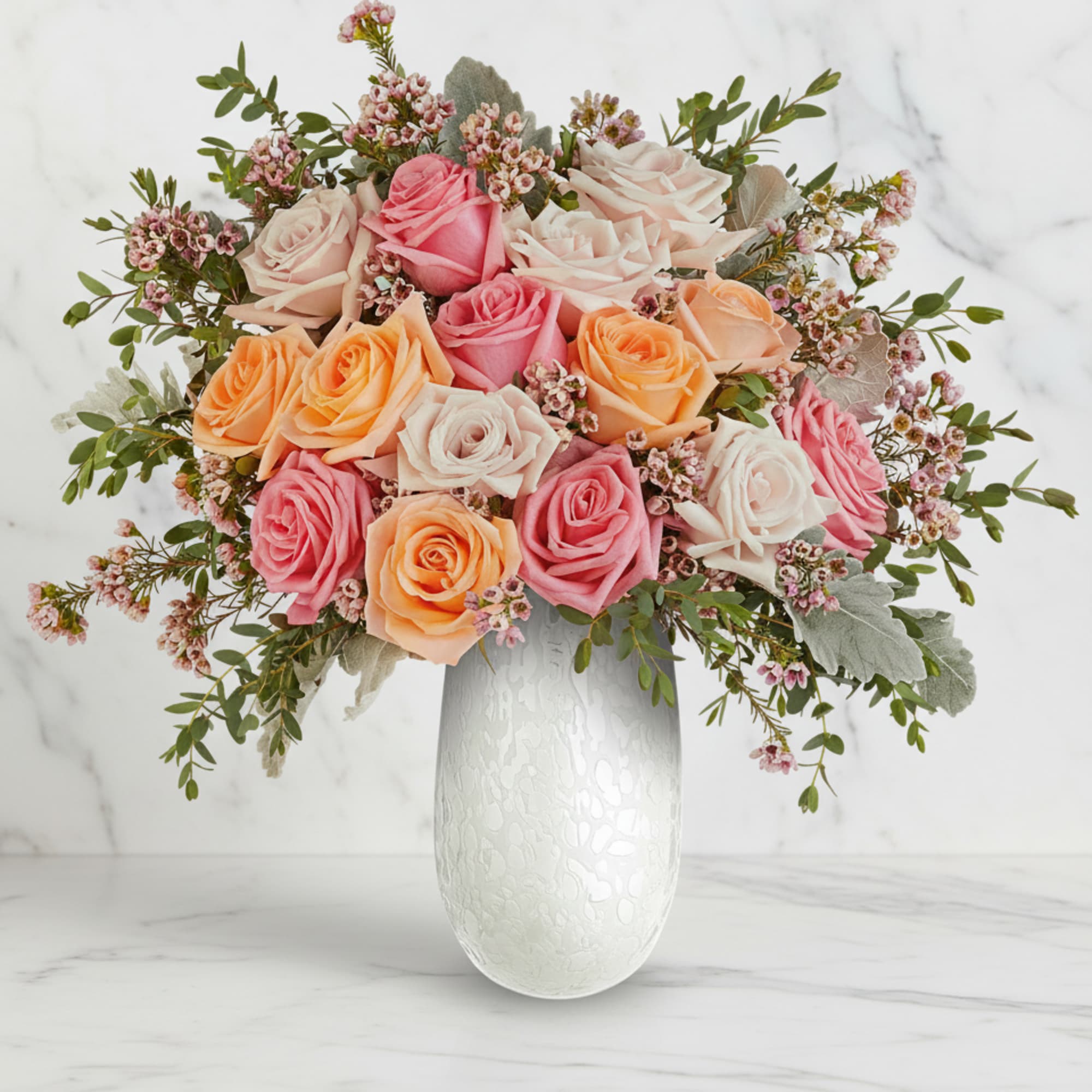 Bouquet of pink, peach, and white roses in a white vase