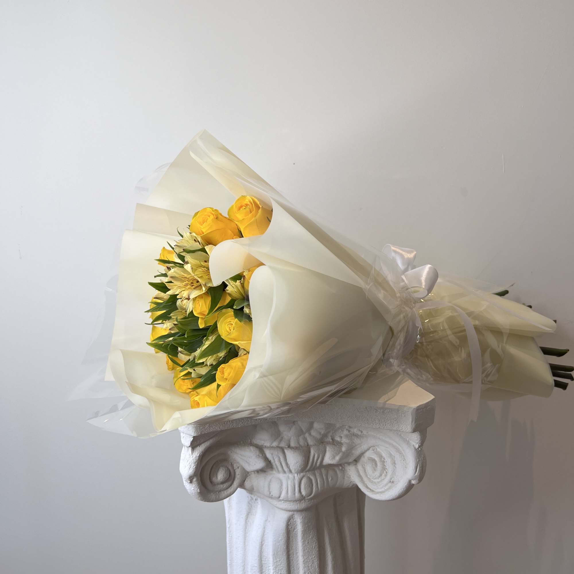 Bouquet of yellow roses and pale flowers wrapped in cream paper