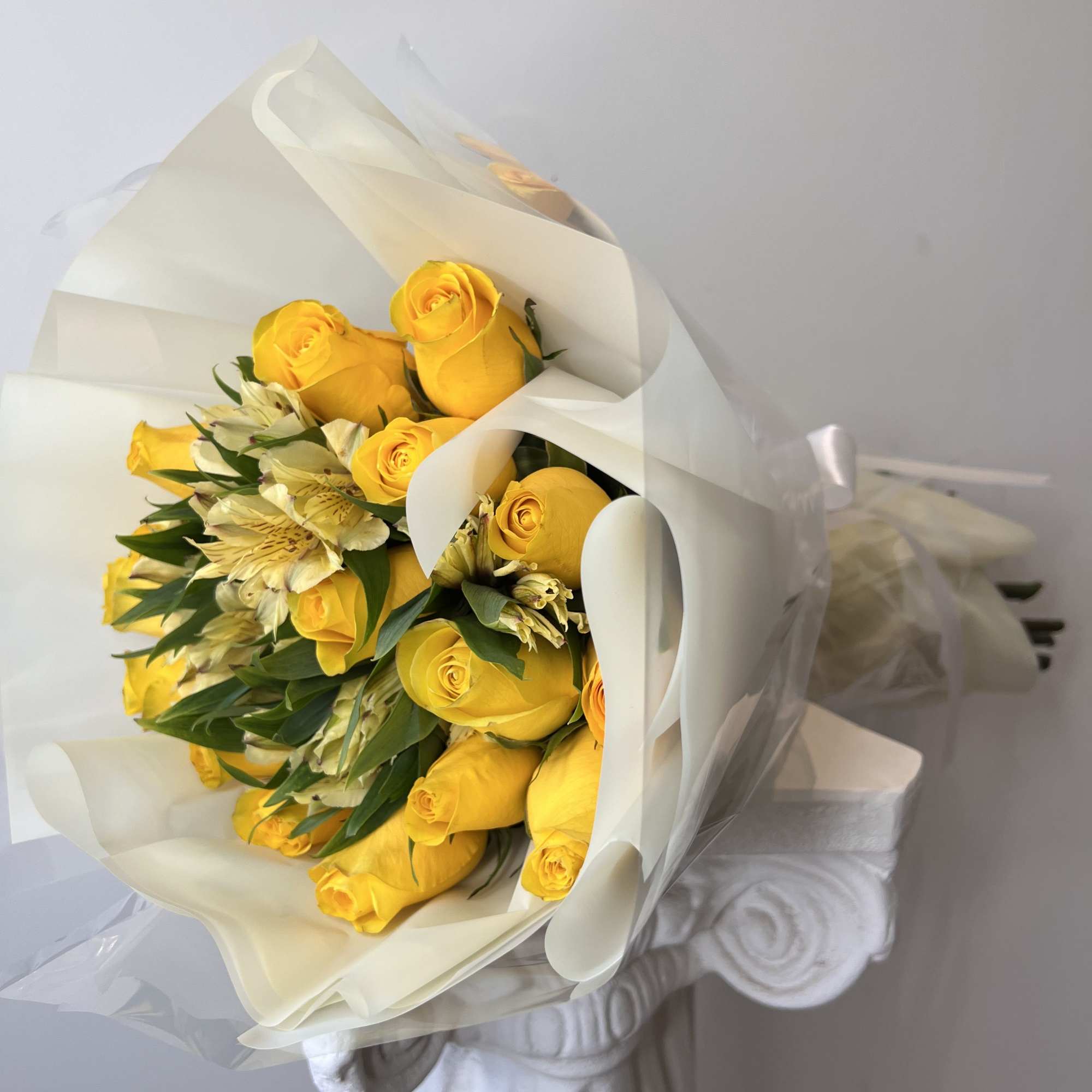 Bouquet of yellow roses and white alstroemeria wrapped in white paper