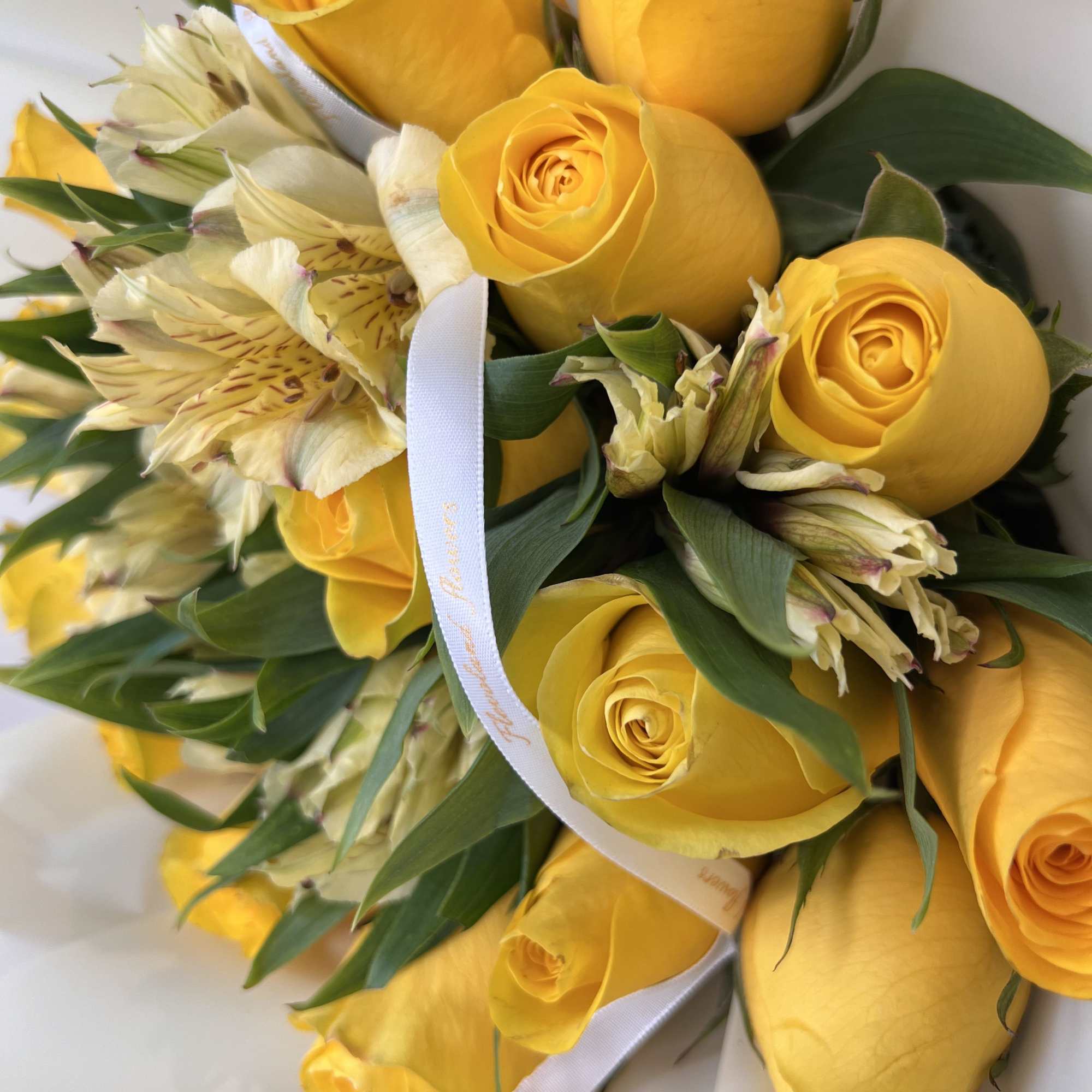 Bouquet of yellow roses and pale alstroemeria tied with a white ribbon