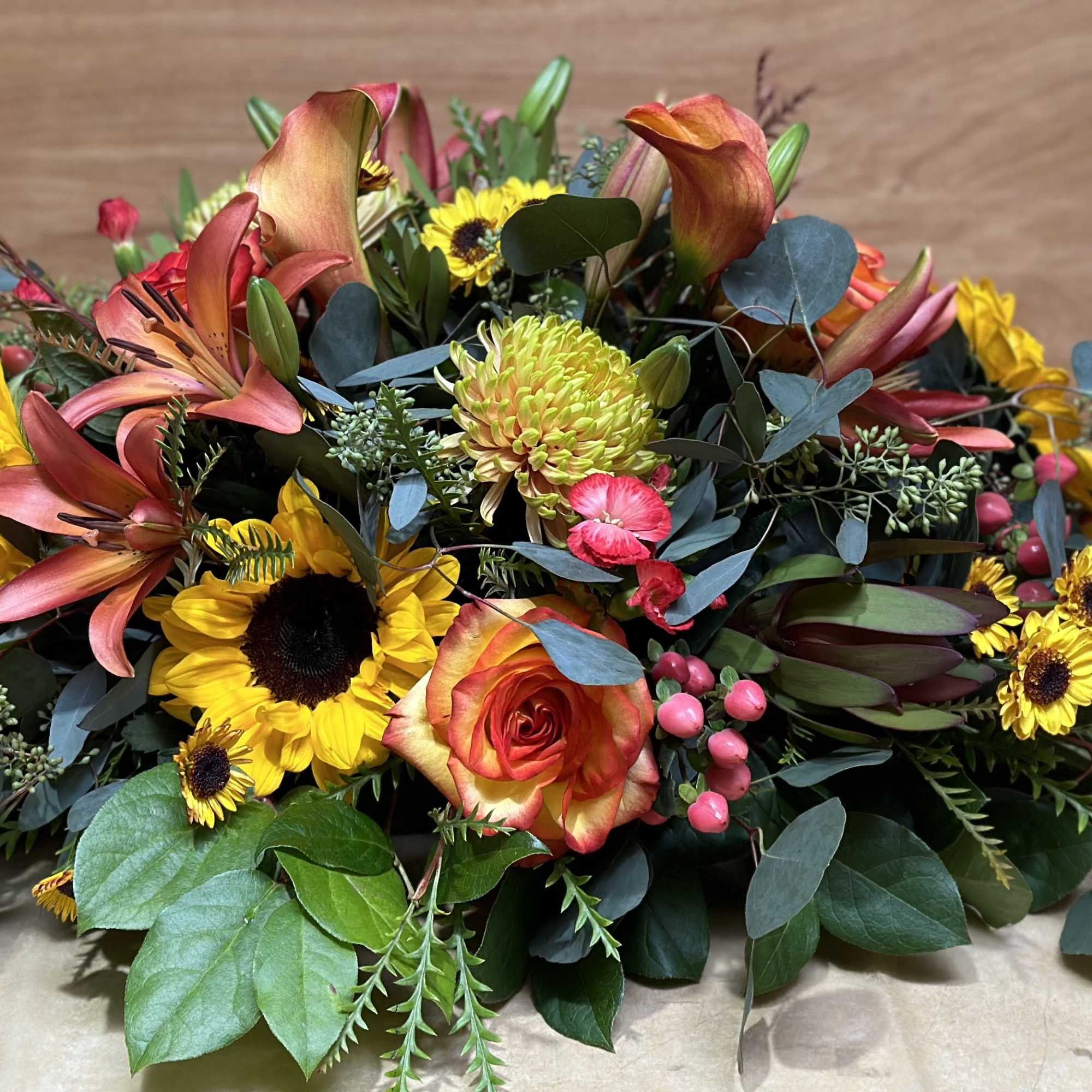 Mixed bouquet with sunflowers, roses, lilies, and eucalyptus on a table