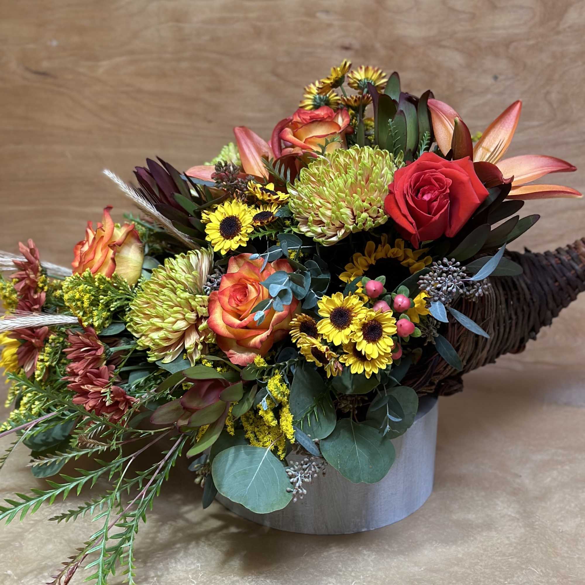 Mixed bouquet in a gray container with roses, lilies, and yellow daisies