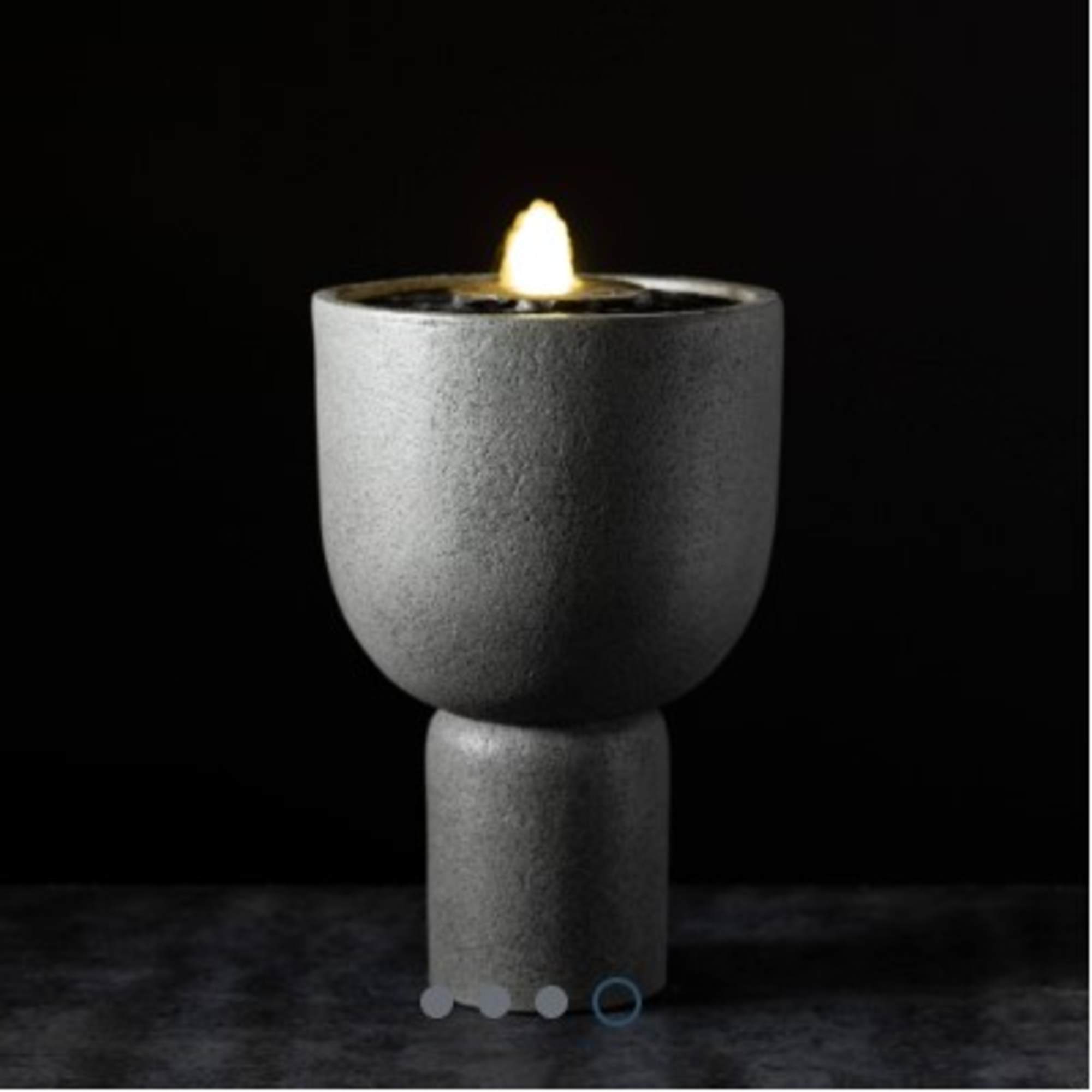 Gray pedestal candle holder with a lit candle on top