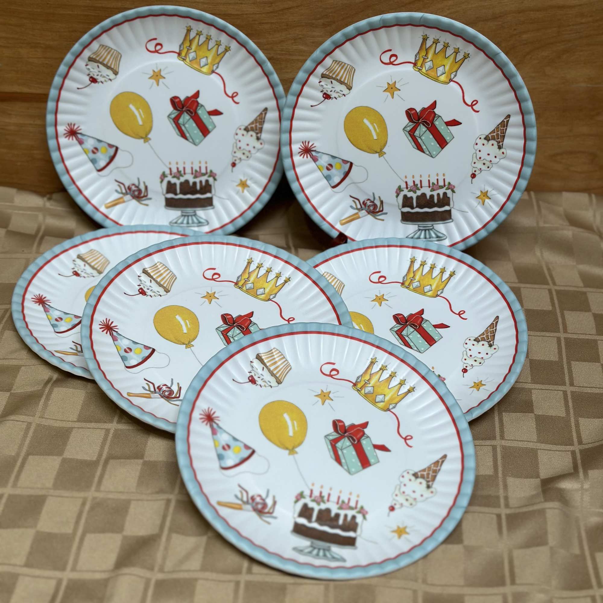 Five birthday-themed paper plates with cakes, balloons, and party hats