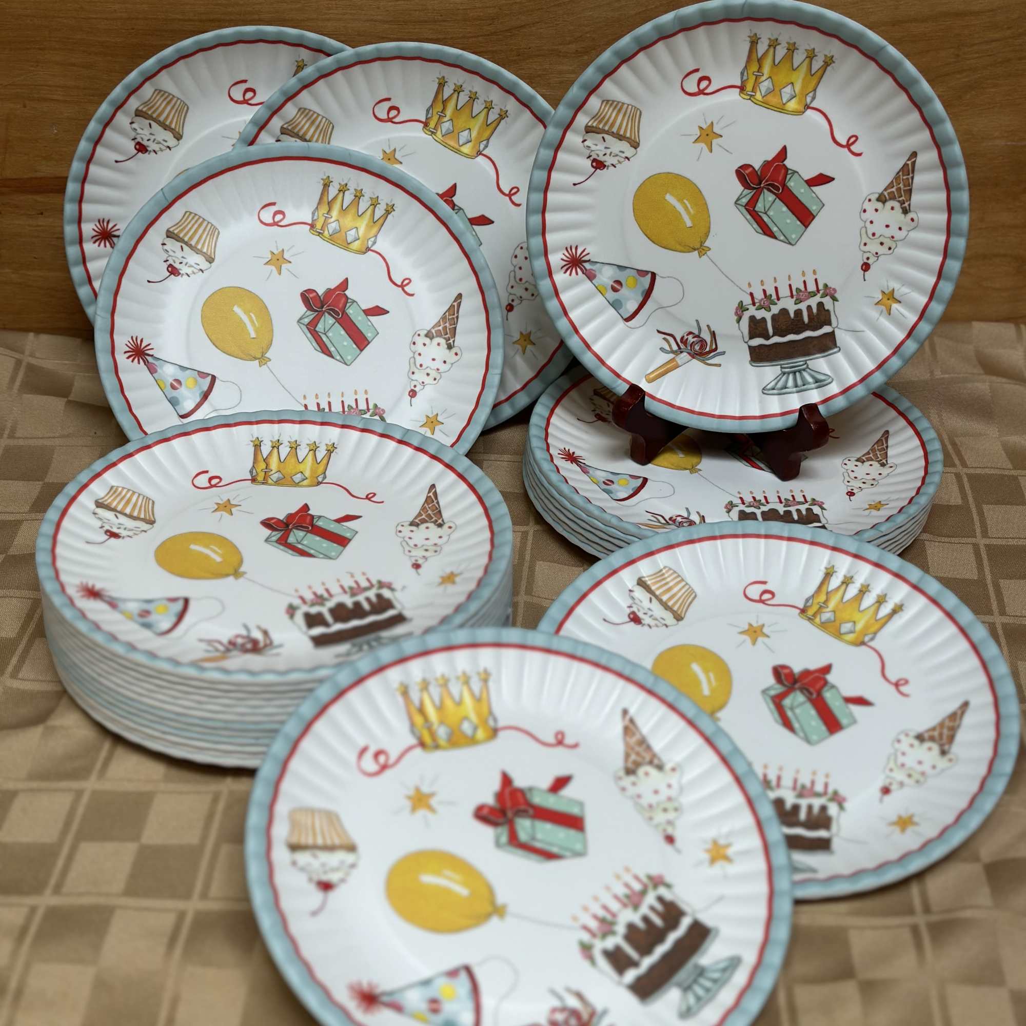 Stack of birthday-themed paper plates with cake, balloons, and gift illustrations