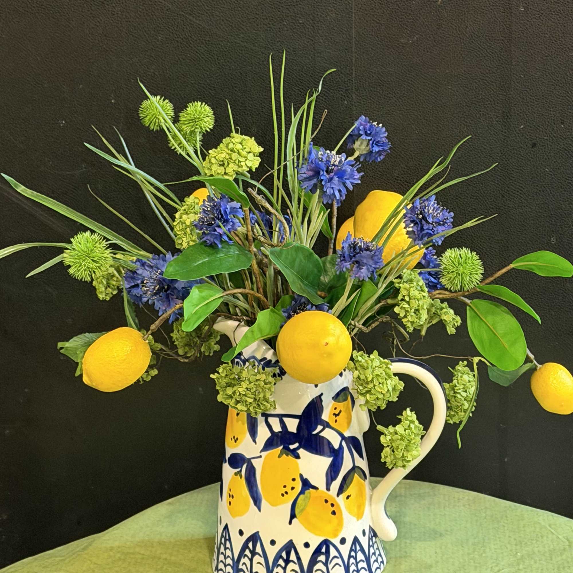 A Tuscan-inspired silk arrangement bursting with lemons, sapphire cornflowers, and green botanicals