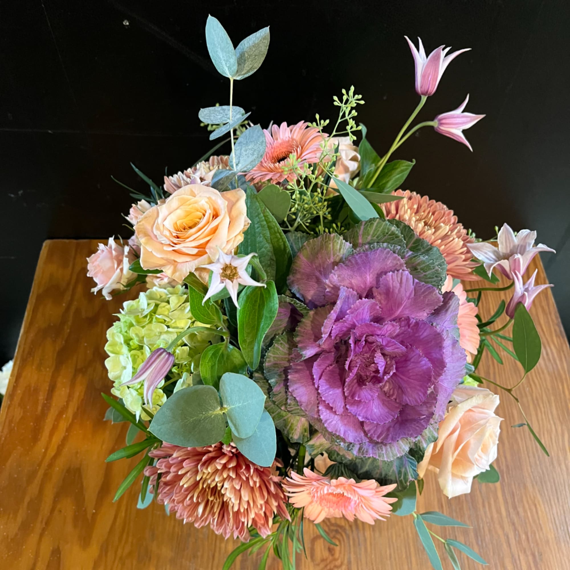 Mixed bouquet with peach roses, purple cabbage, and pink daisies
