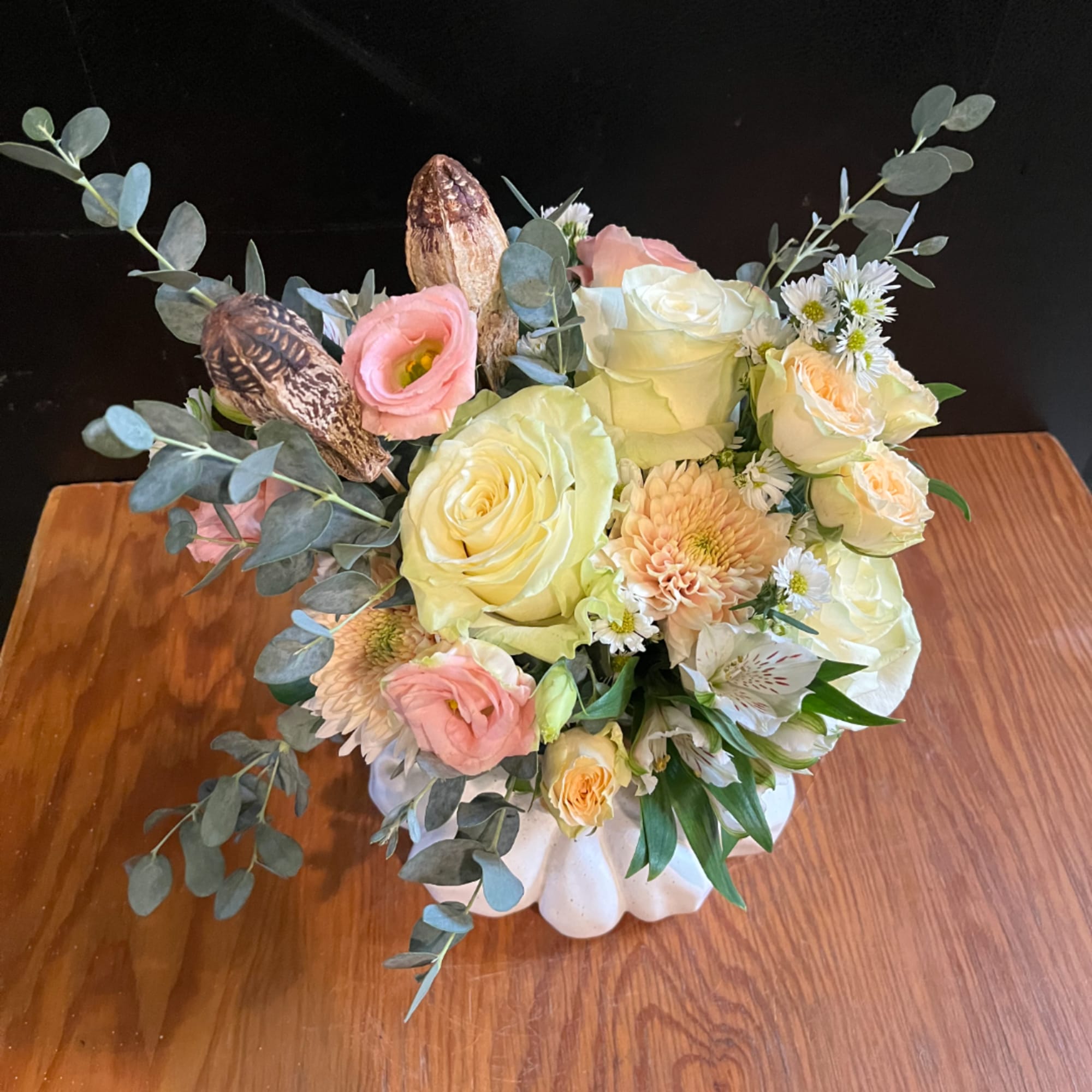 Bouquet of pale roses and peach flowers in a white vase